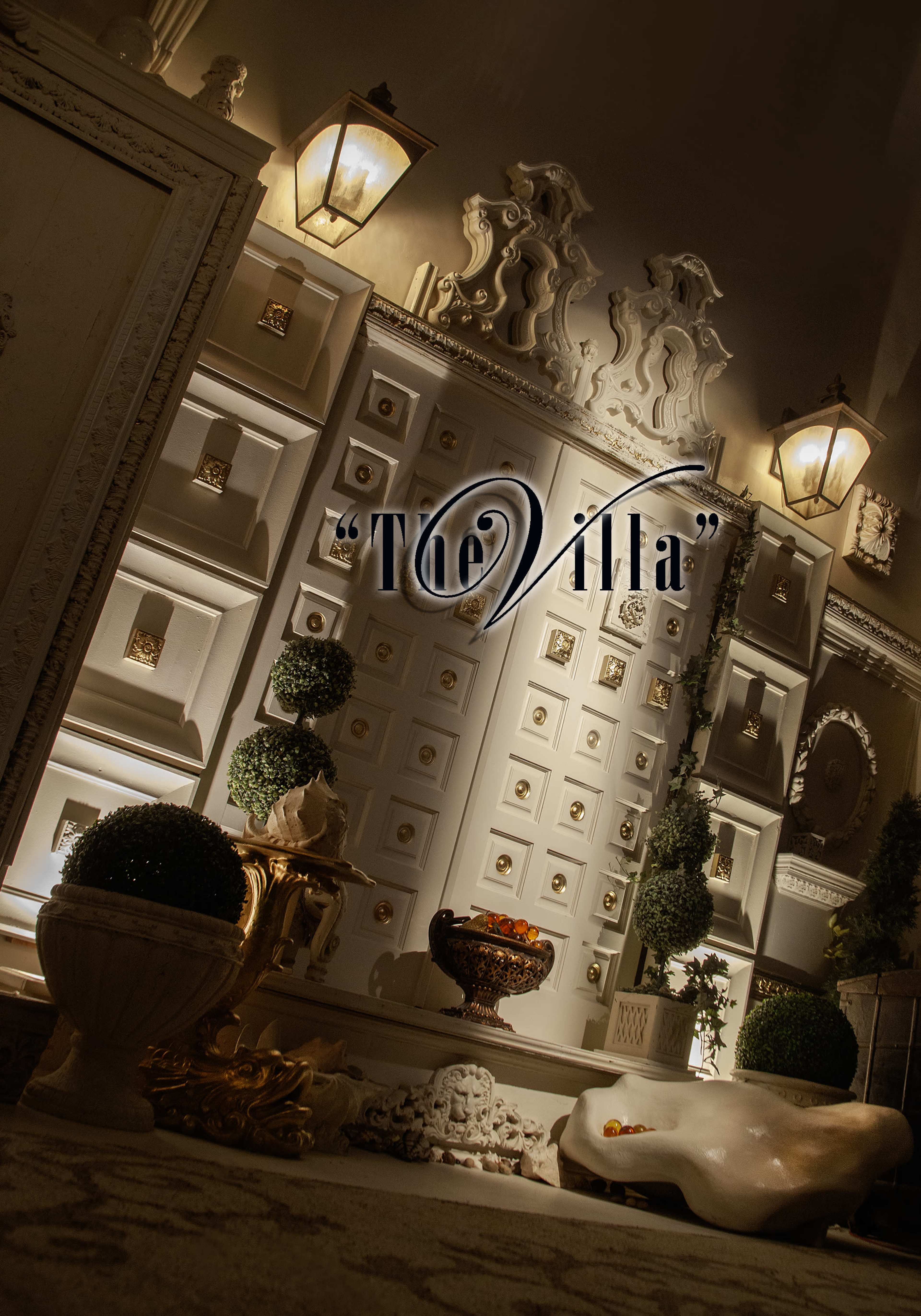 The image features an elegantly designed interior space with ornate architectural details, decorative lanterns, and greenery.