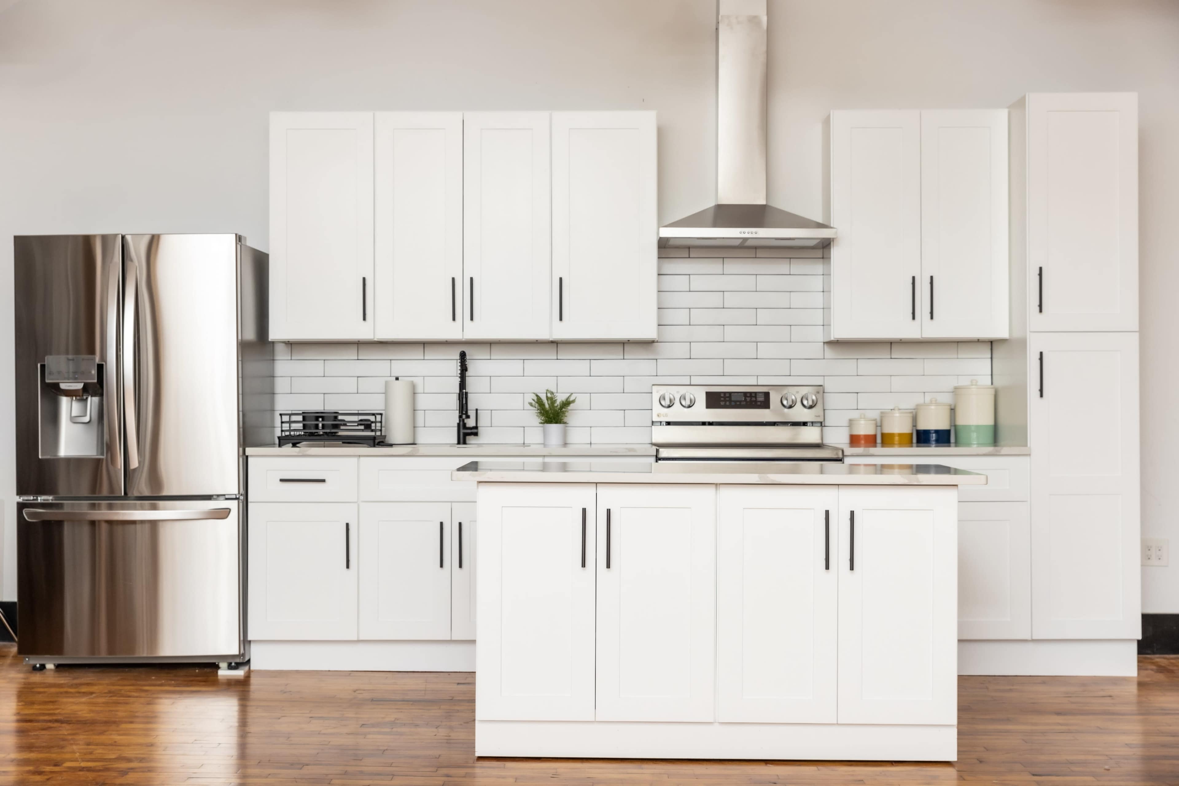 A modern kitchen features white cabinets, stainless steel appliances, a gas stove, and a central island with a polished surface.