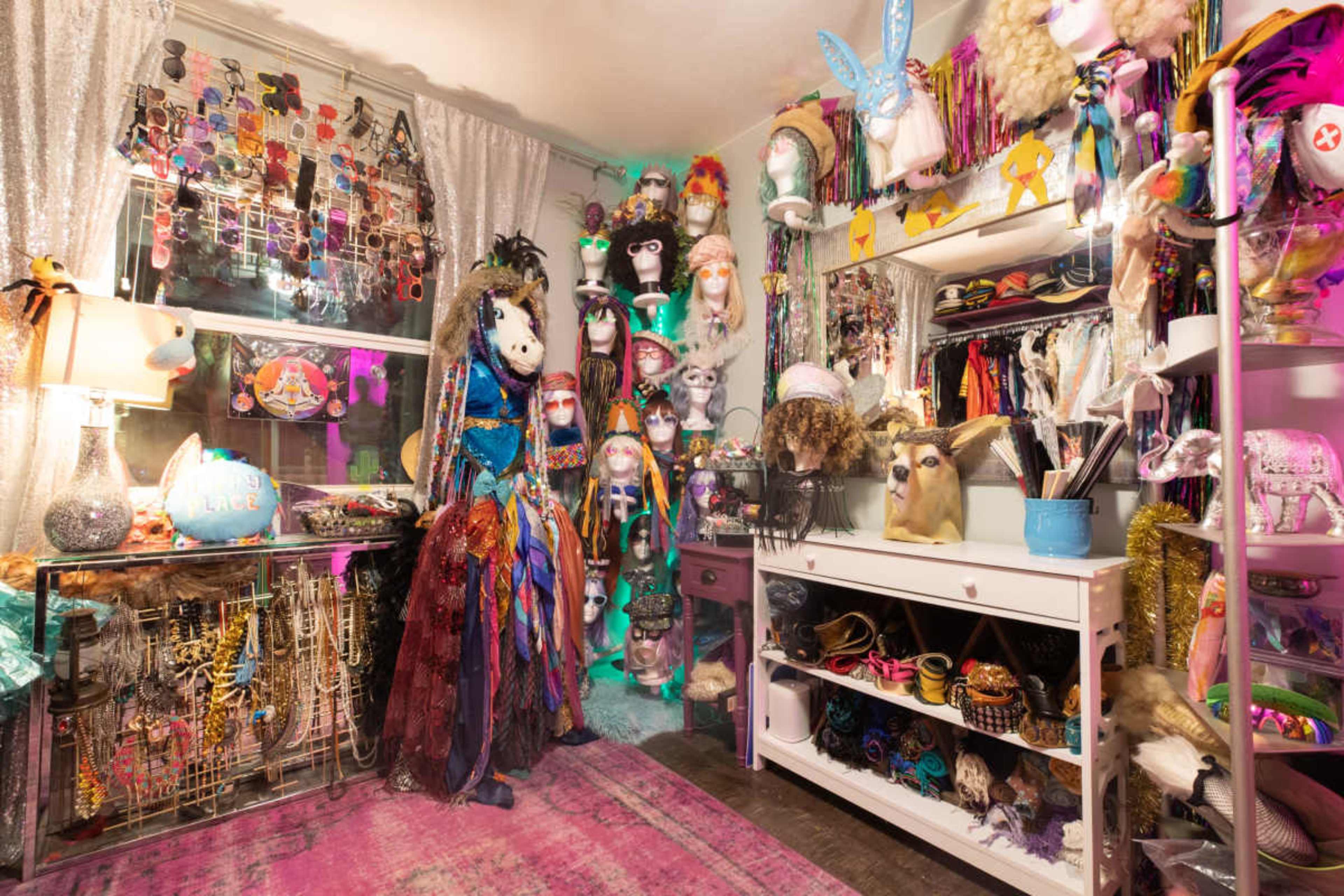 A colorful and eclectic dressing room filled with costumes, accessories, and various decorative items.