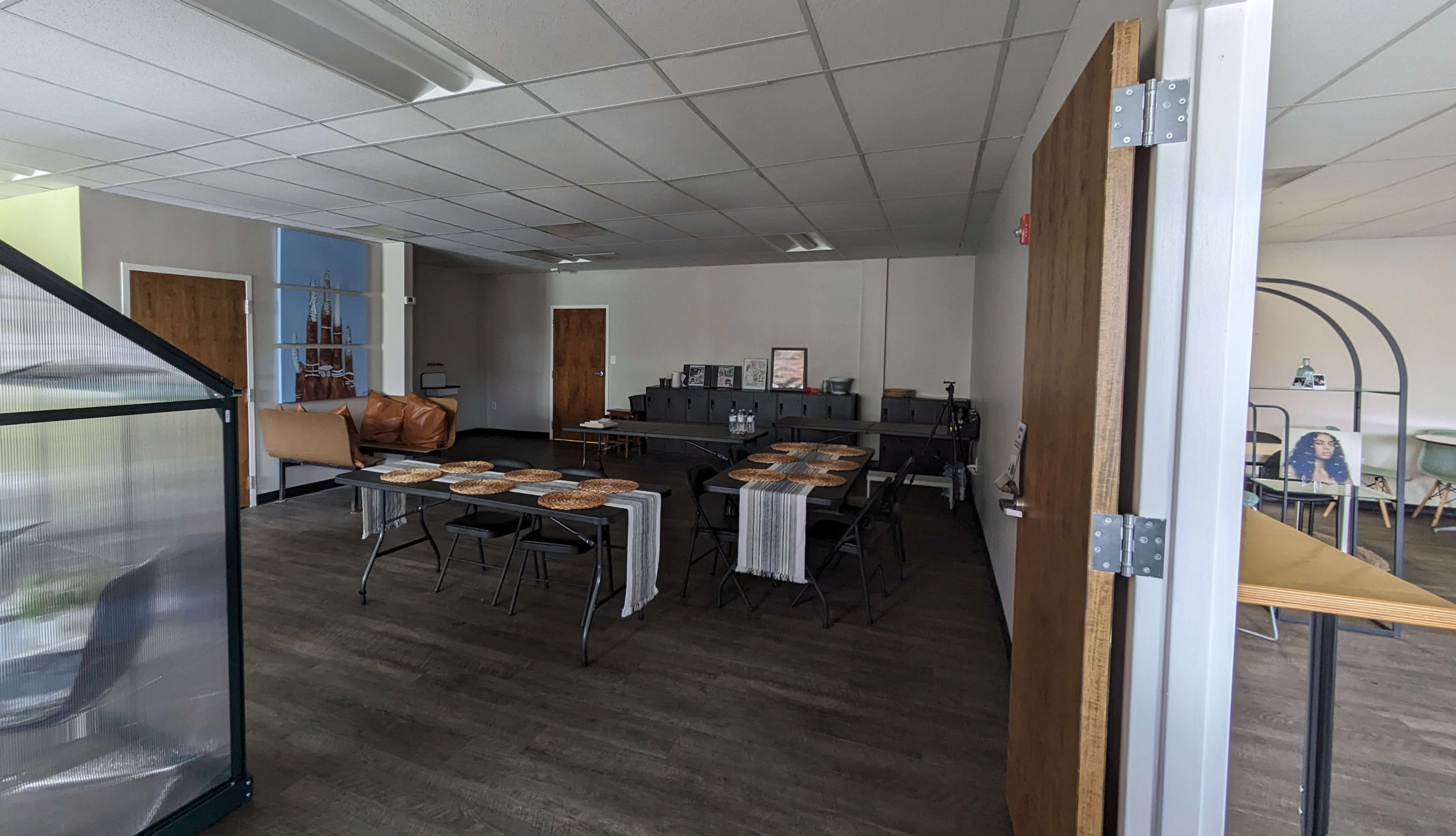 A spacious room with a set of tables laid out for dining, surrounded by chairs and minimalistic furniture.