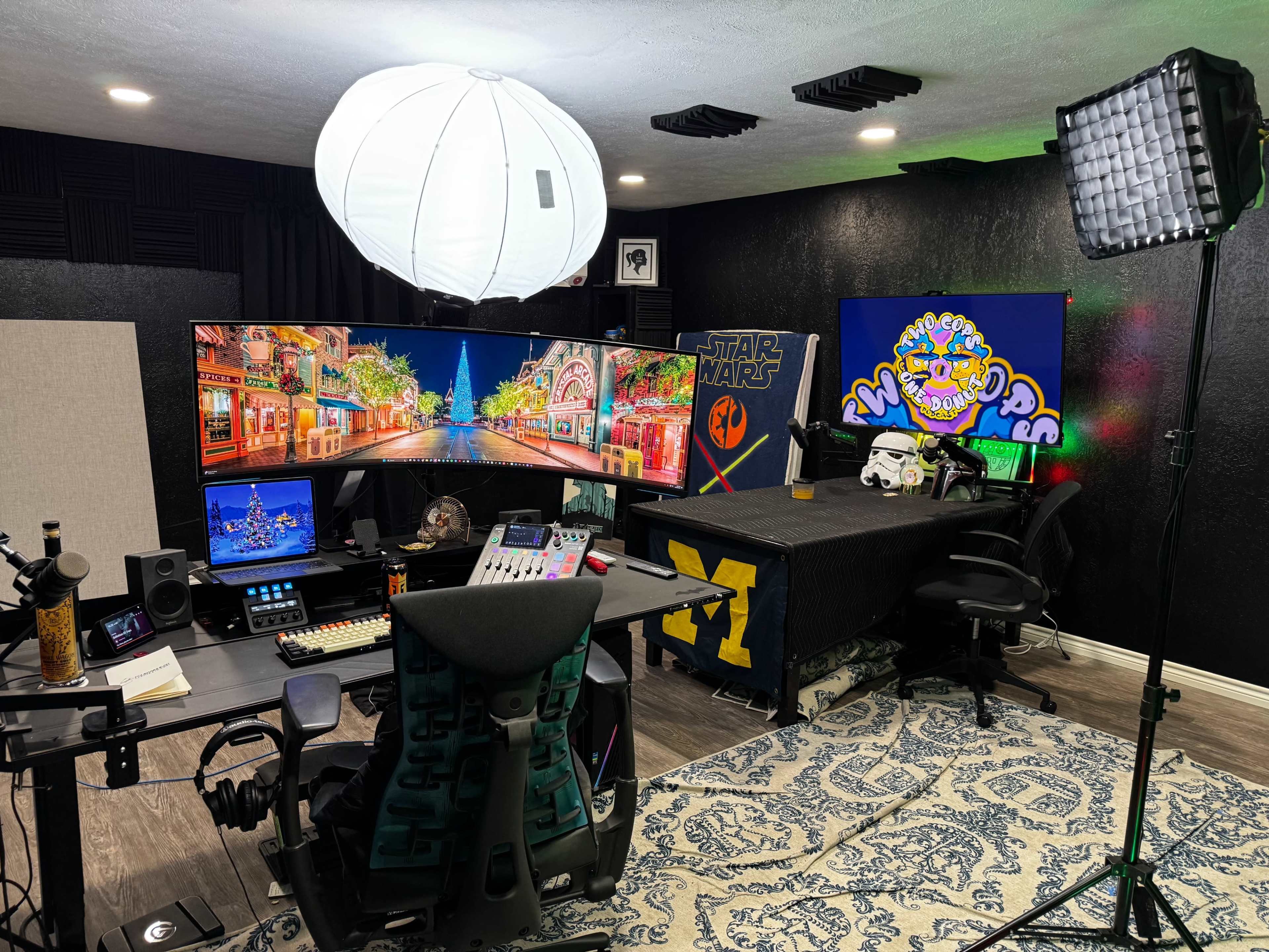 The image depicts a modern home studio setup featuring multiple screens, colorful decorations, and professional lighting equipment.