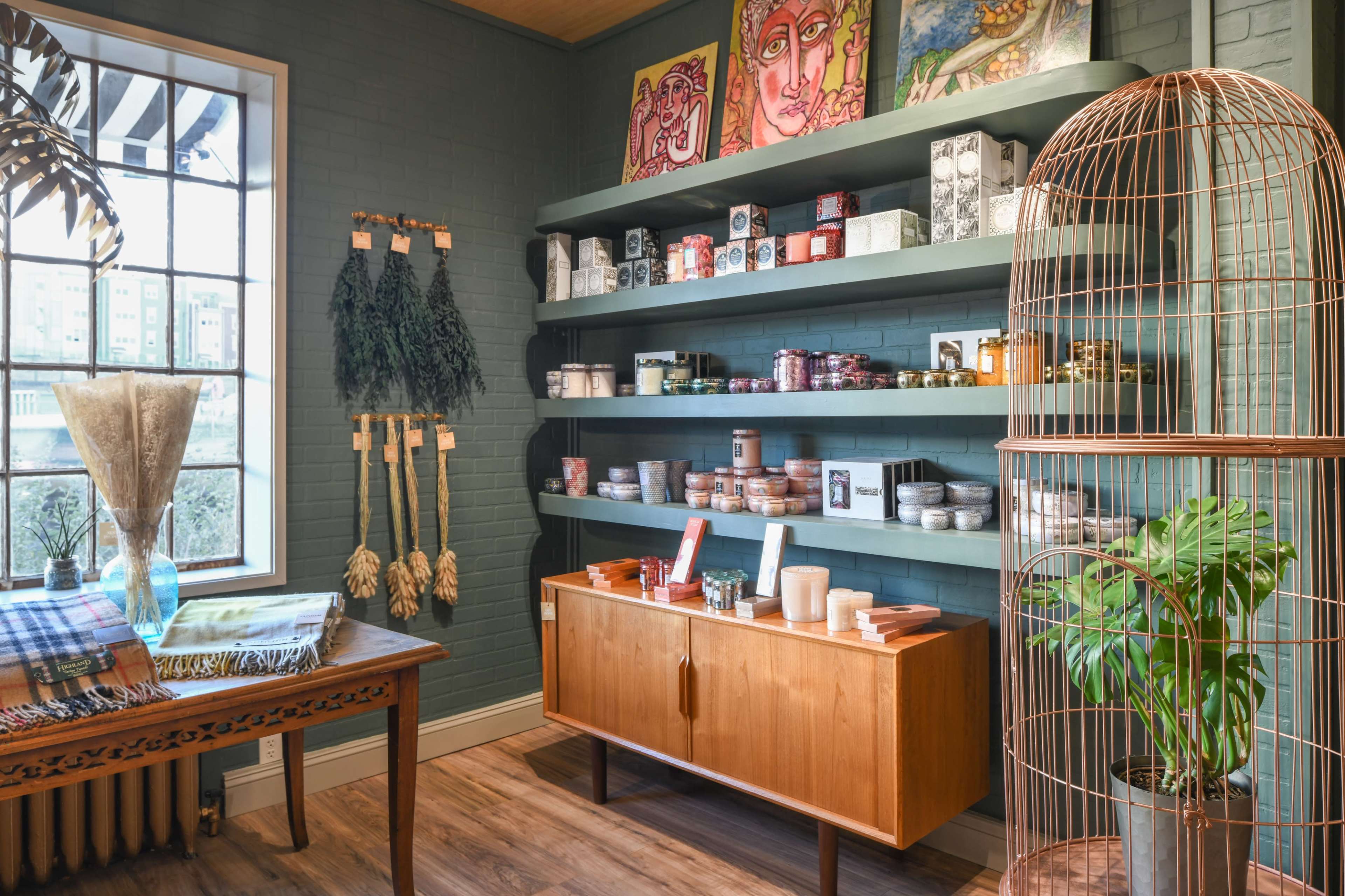 A well-organized interior of a shop with shelves displaying various jars and products, a wooden table, and decorative items including plants and artwork.