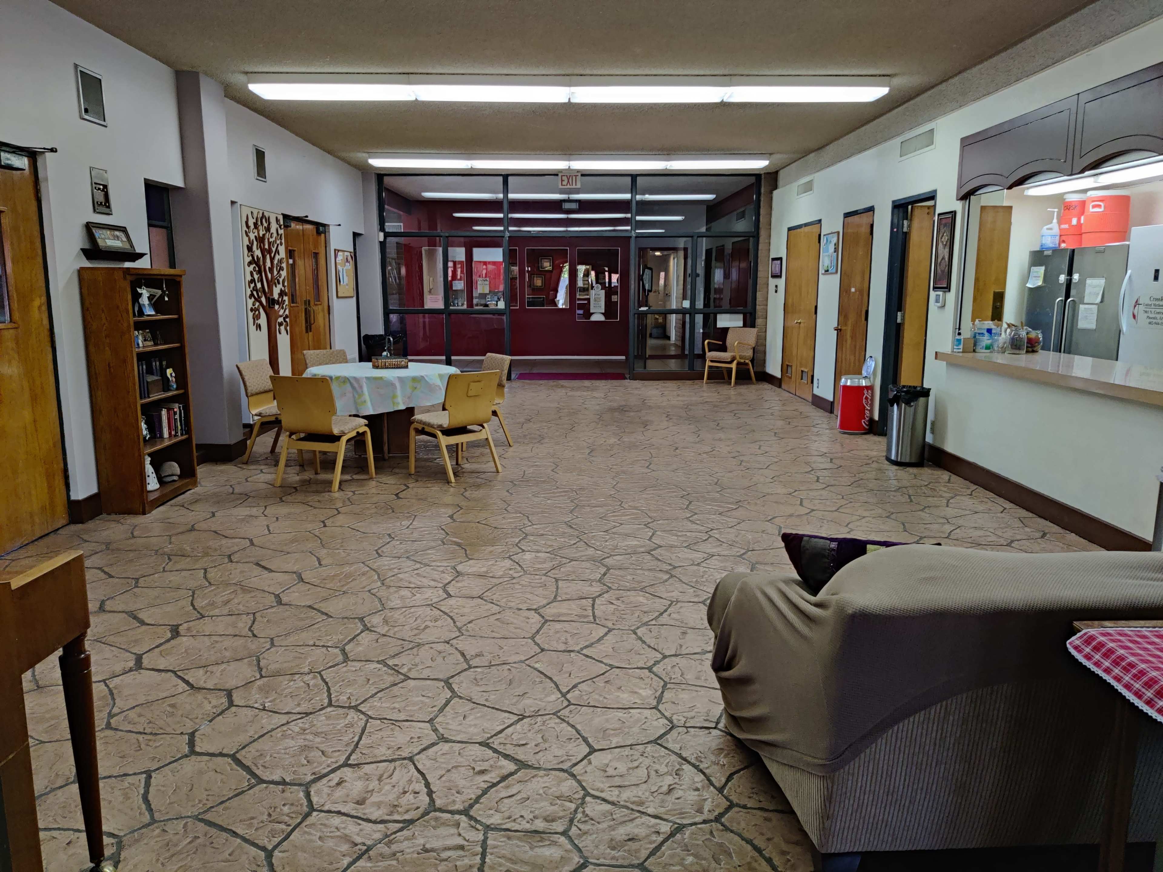 A spacious hallway with a seating area, a dining table, and doors leading to another room.