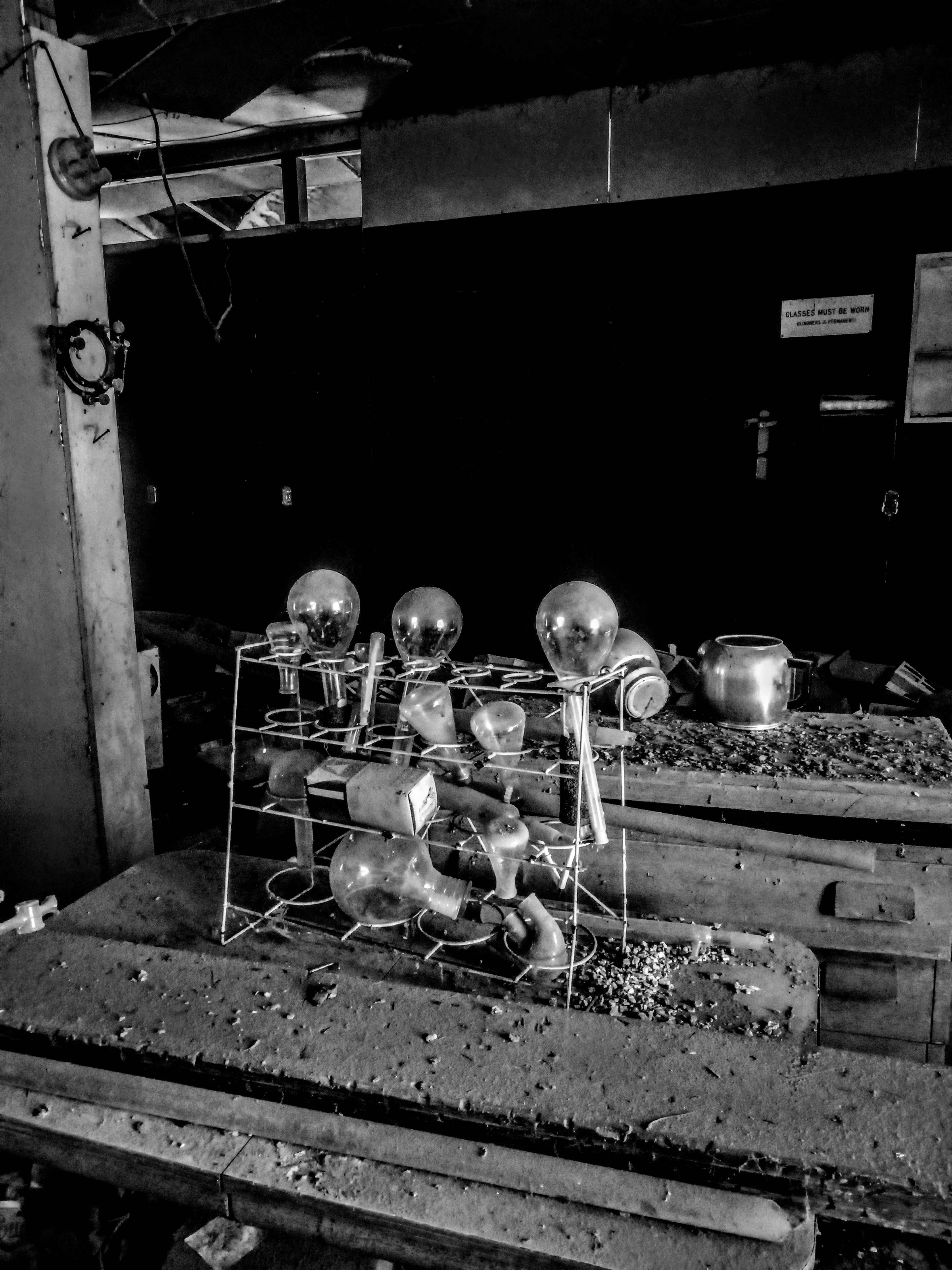 The image shows a disorganized assembly of glass light bulbs on a dusty rack in an abandoned space.