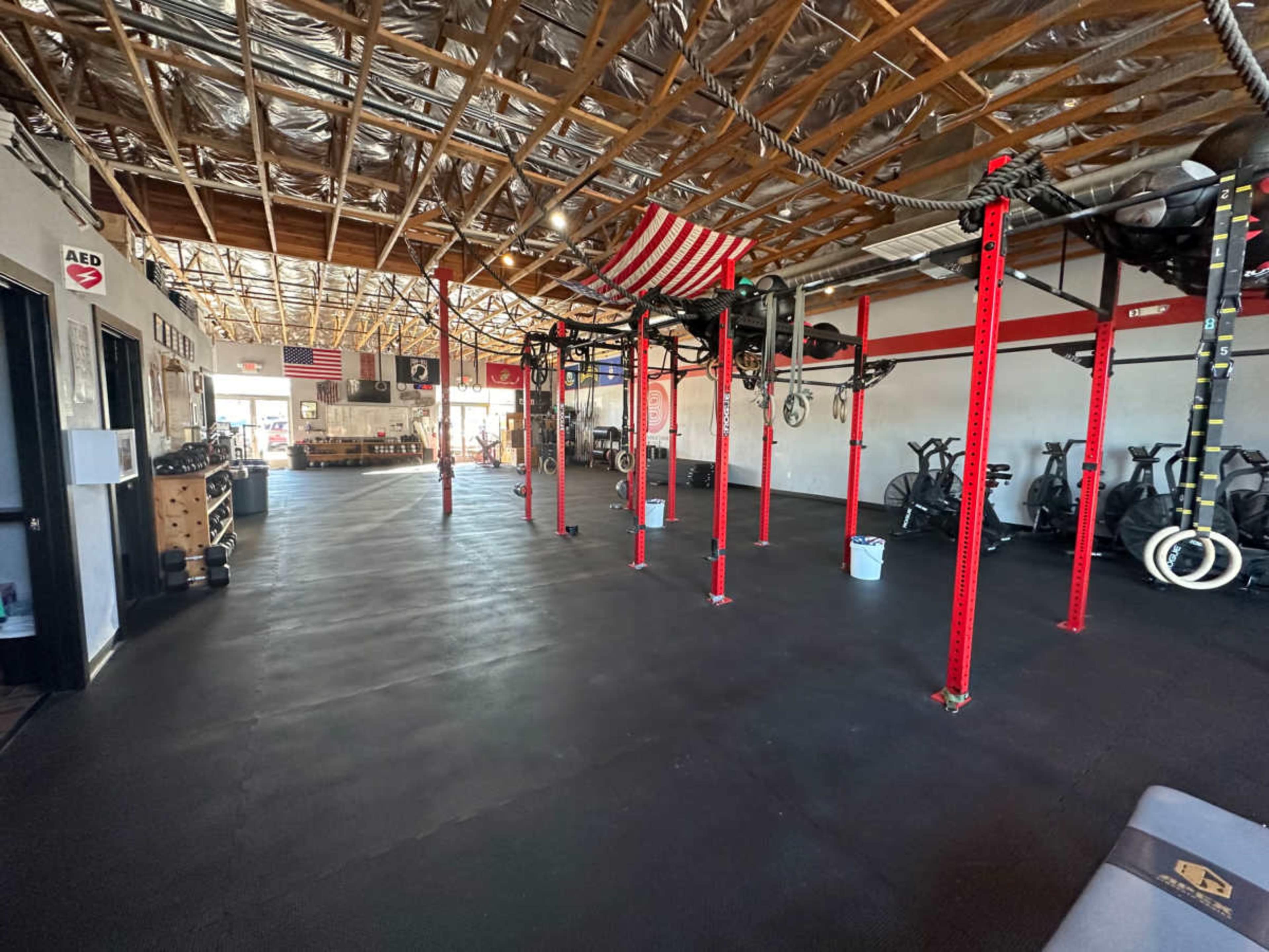 A spacious gym with red support beams, various exercise equipment, and an open floor plan.
