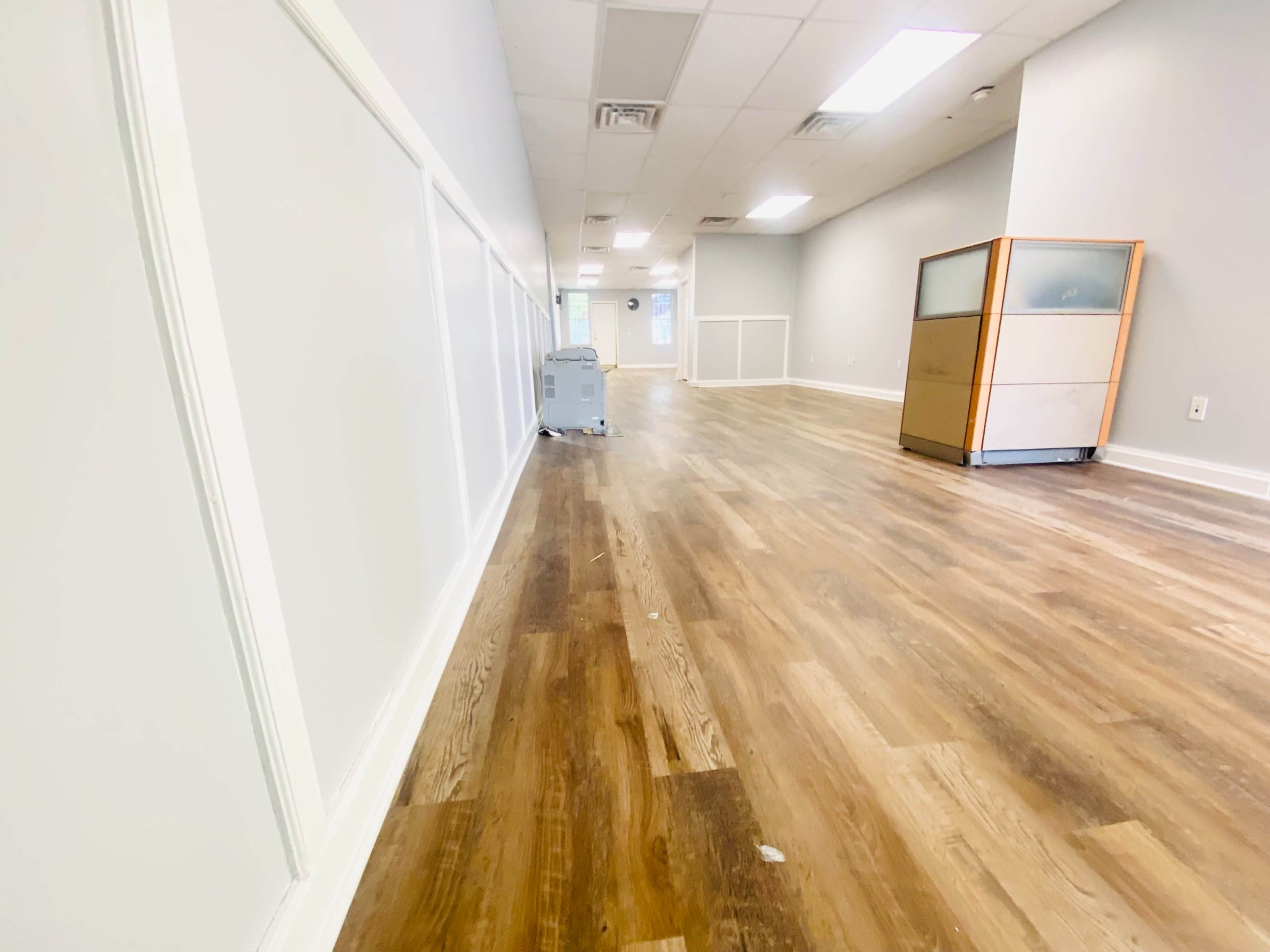 A long, empty hallway with wooden flooring and a piece of furniture at the end.