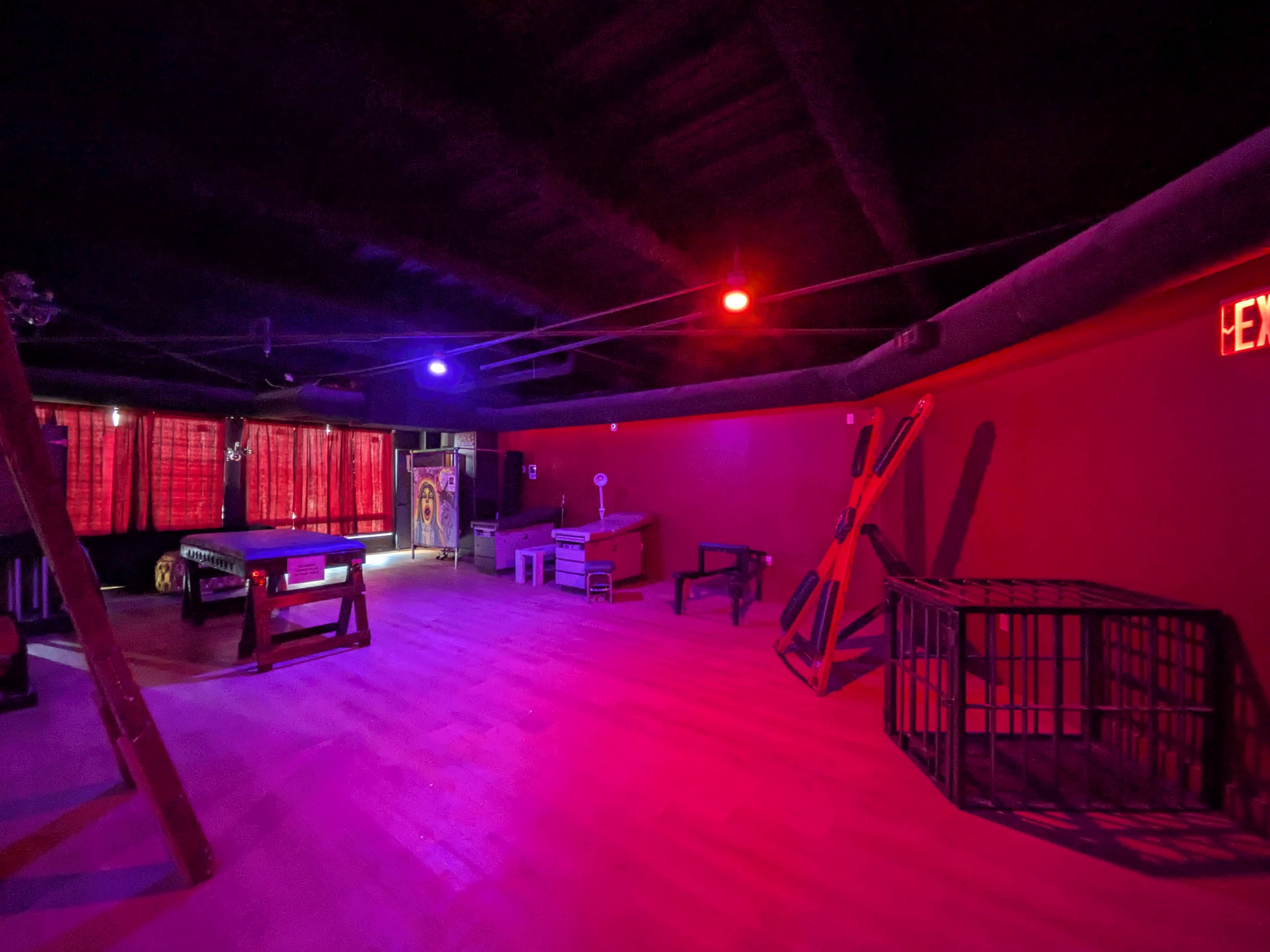 The room features a wooden floor, various pieces of furniture, and colored lights casting a purple and red glow.