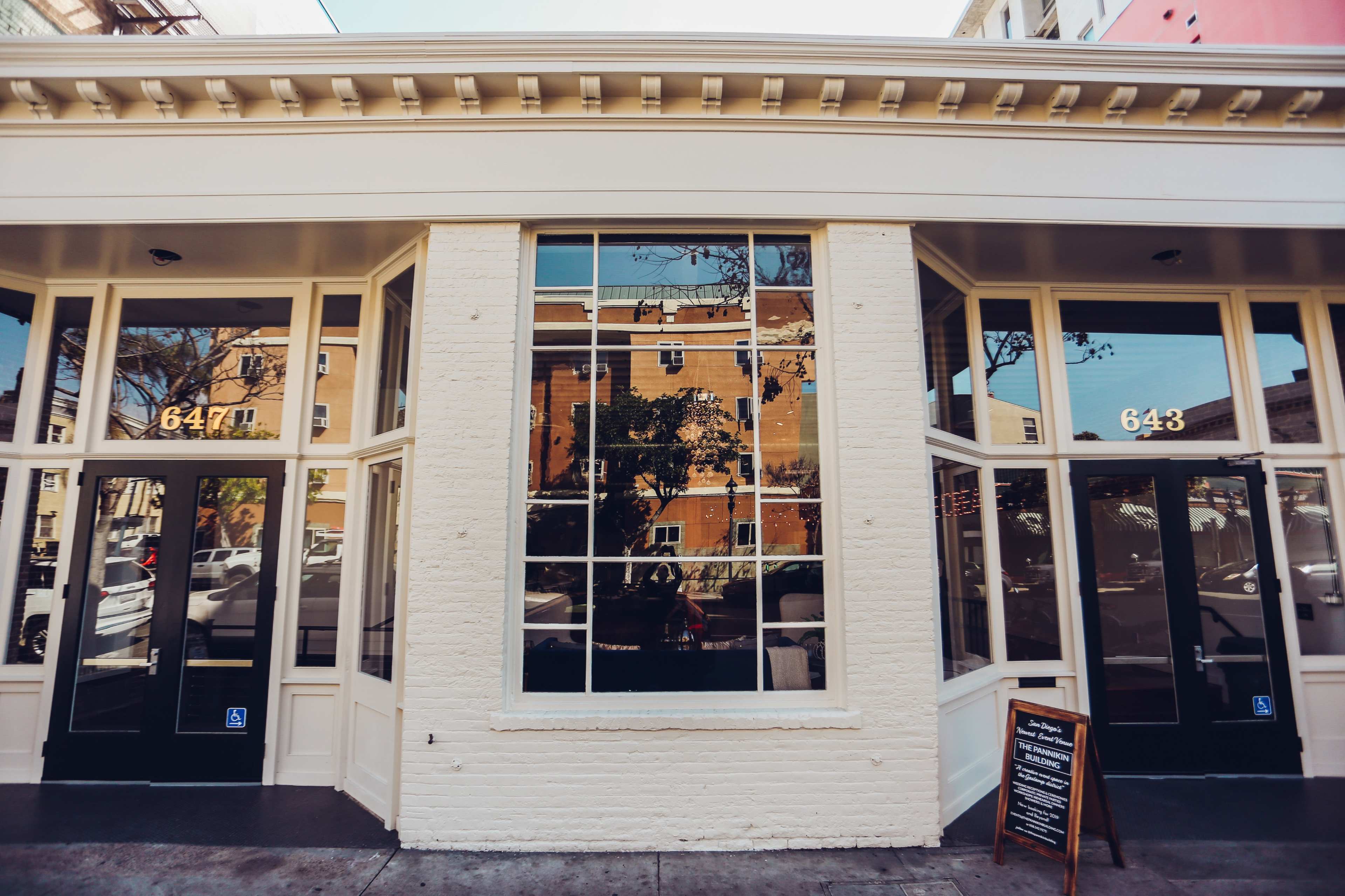 A building storefront with large windows reflecting the surroundings, featuring two door entrances labeled "647" and "648."