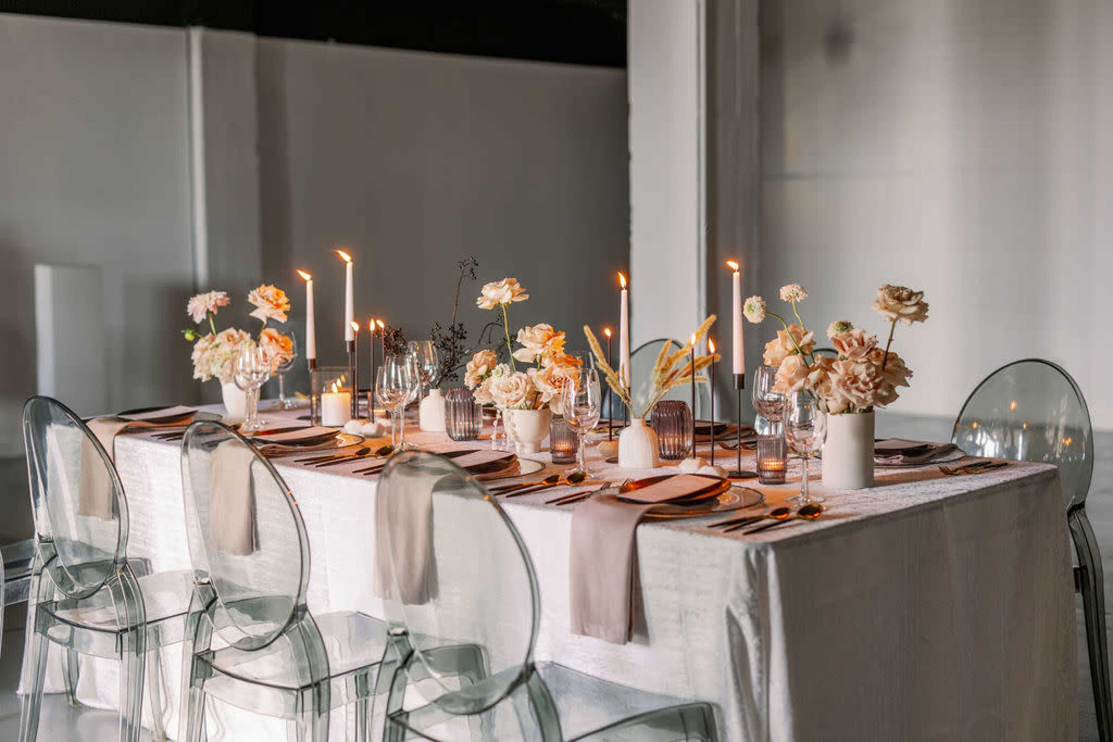 A decorated dining table is set with flowers, candles, and elegant tableware in a modern interior.