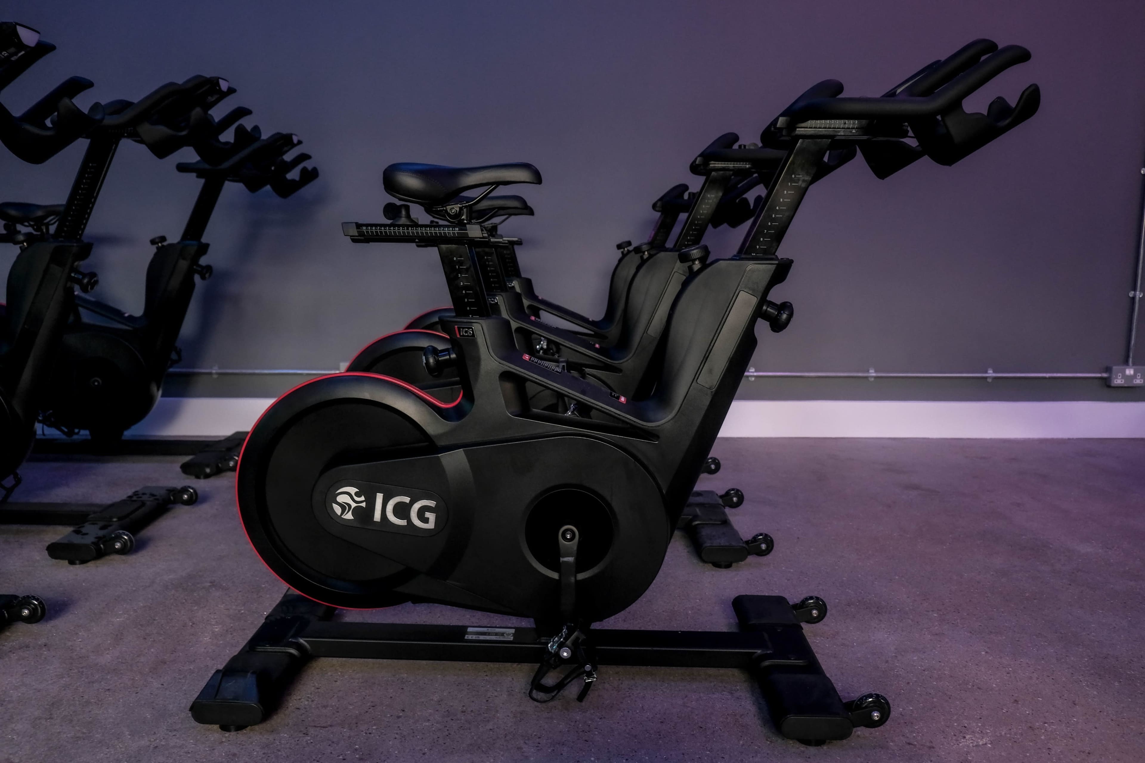 The image shows a row of stationary exercise bikes arranged in a fitness studio.