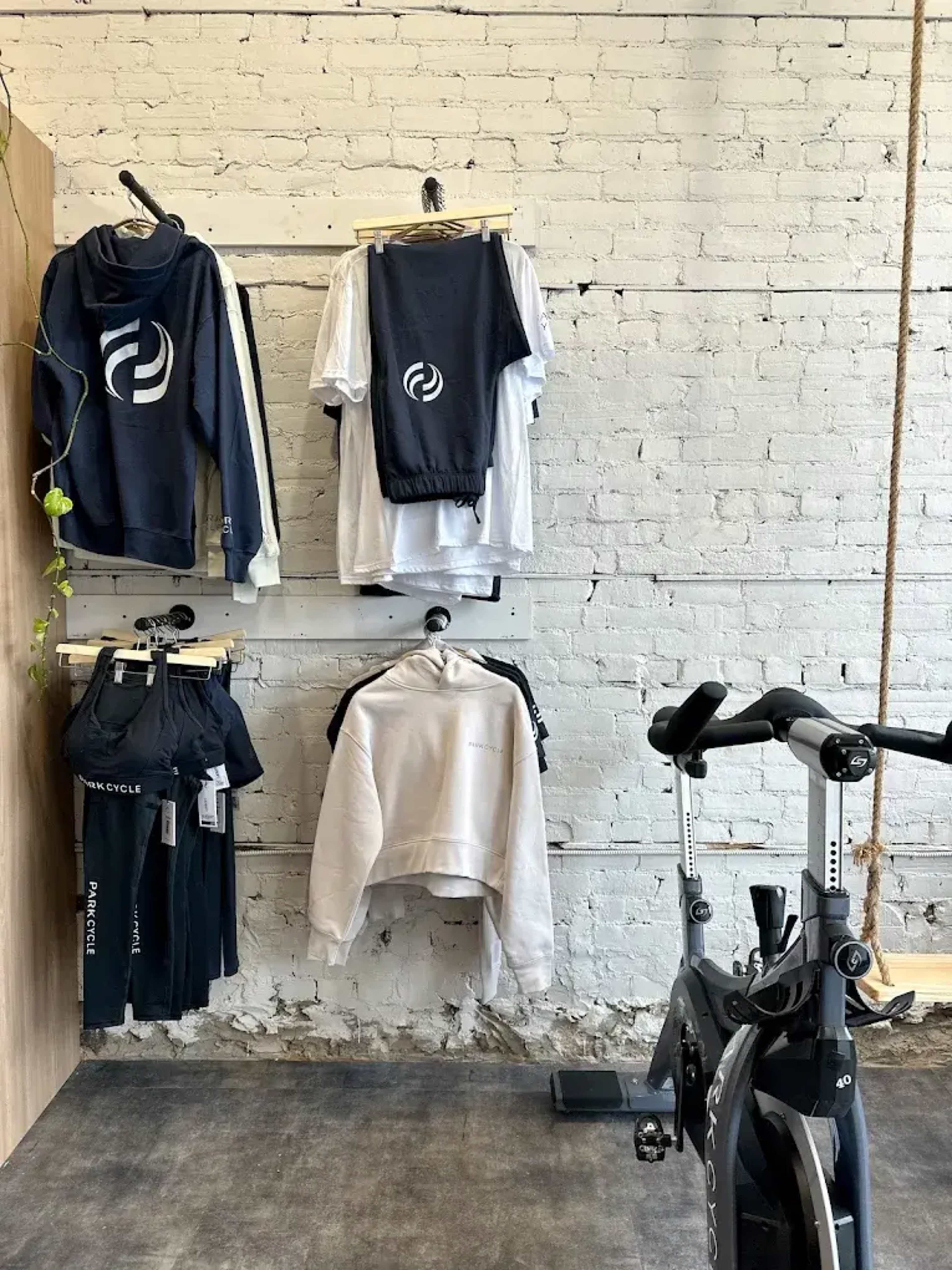 The image shows a fitness clothing display on a brick wall alongside a stationary exercise bike.