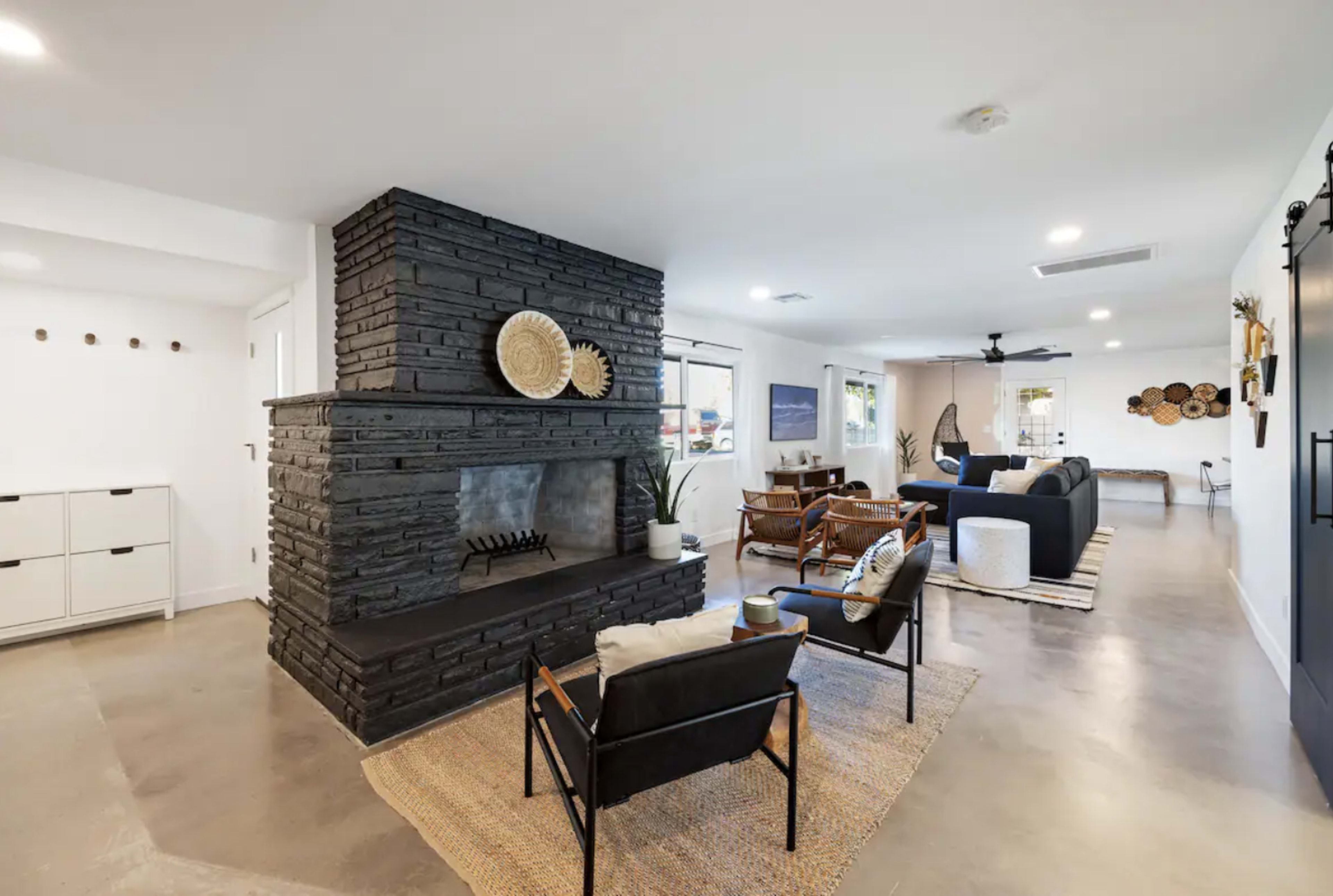 A spacious living area featuring a dark stone fireplace, modern furniture, and decorative wall elements.