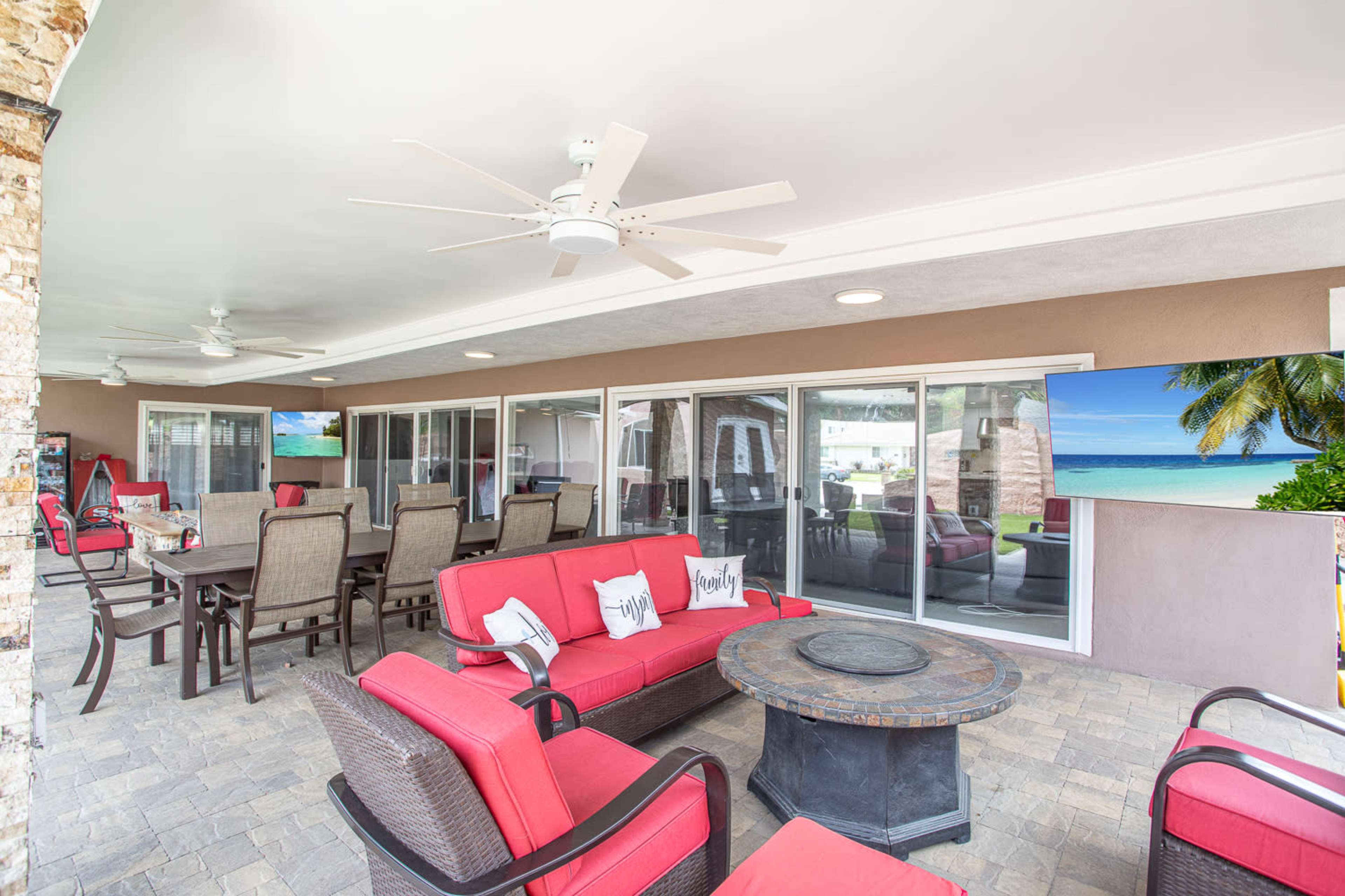 A patio area with red seating, a round fire pit, and large glass doors leading to an indoor space.