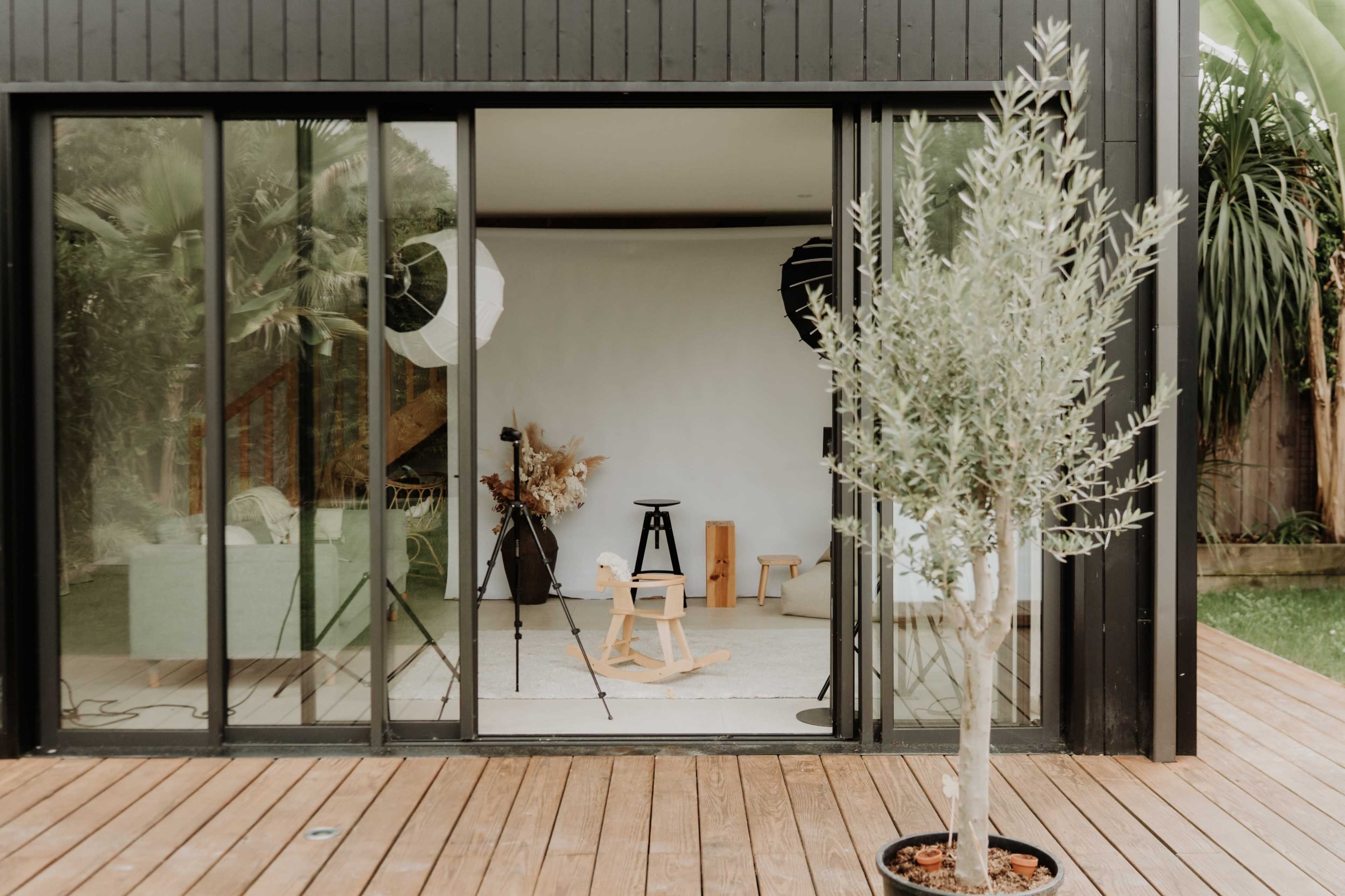 A modern outdoor space features large glass doors opening to a minimalistic setup with photography equipment and decorative elements.