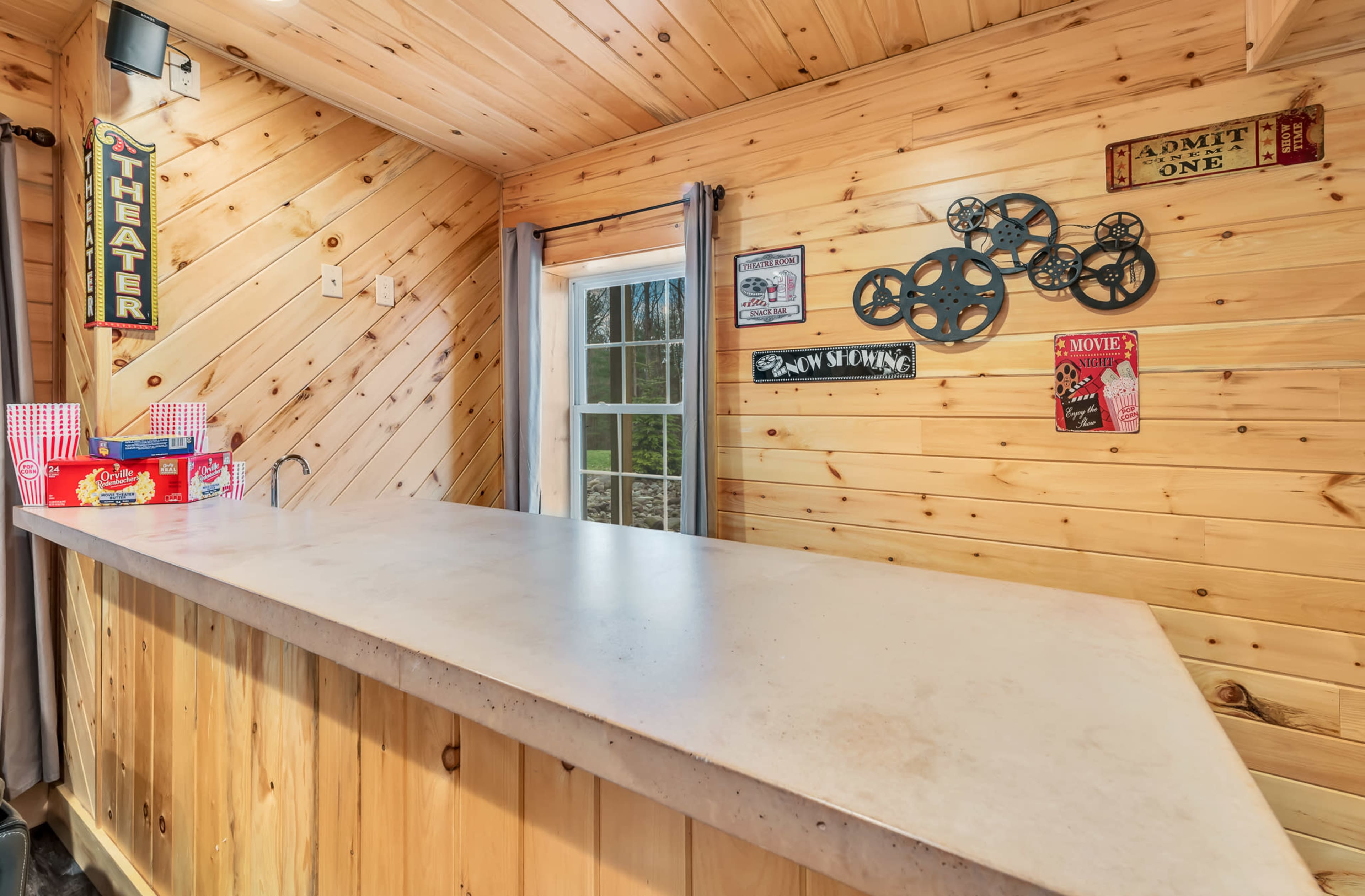 A wooden bar area with a concrete countertop, featuring vintage movie-themed decorations on the walls.