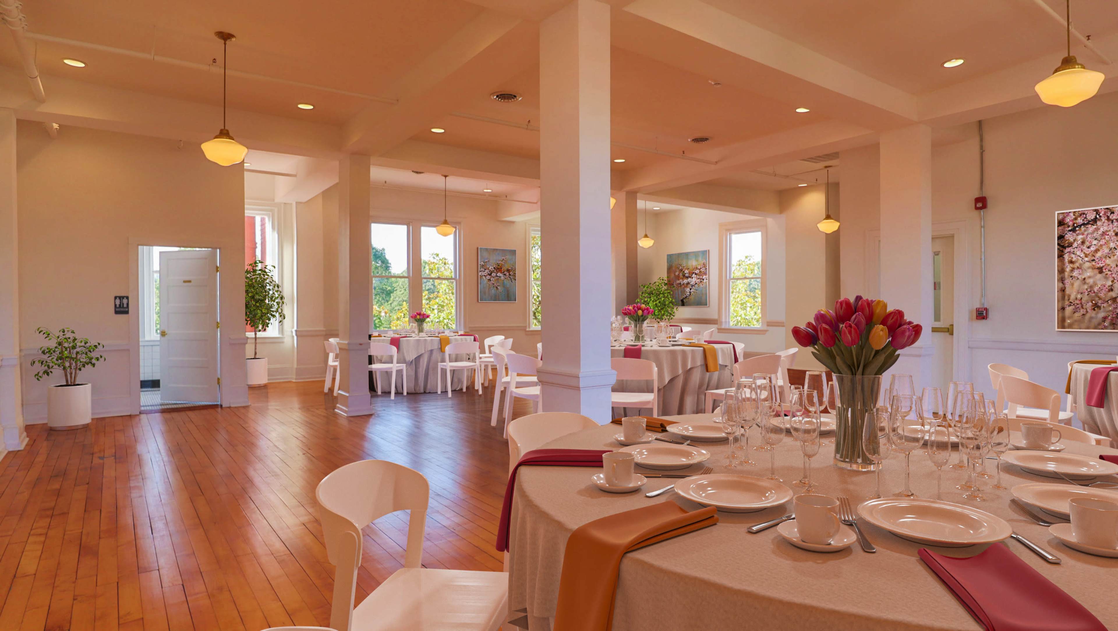 A spacious dining area with tables set for a meal, featuring white chairs, floral centerpieces, and large windows allowing natural light to illuminate the room.