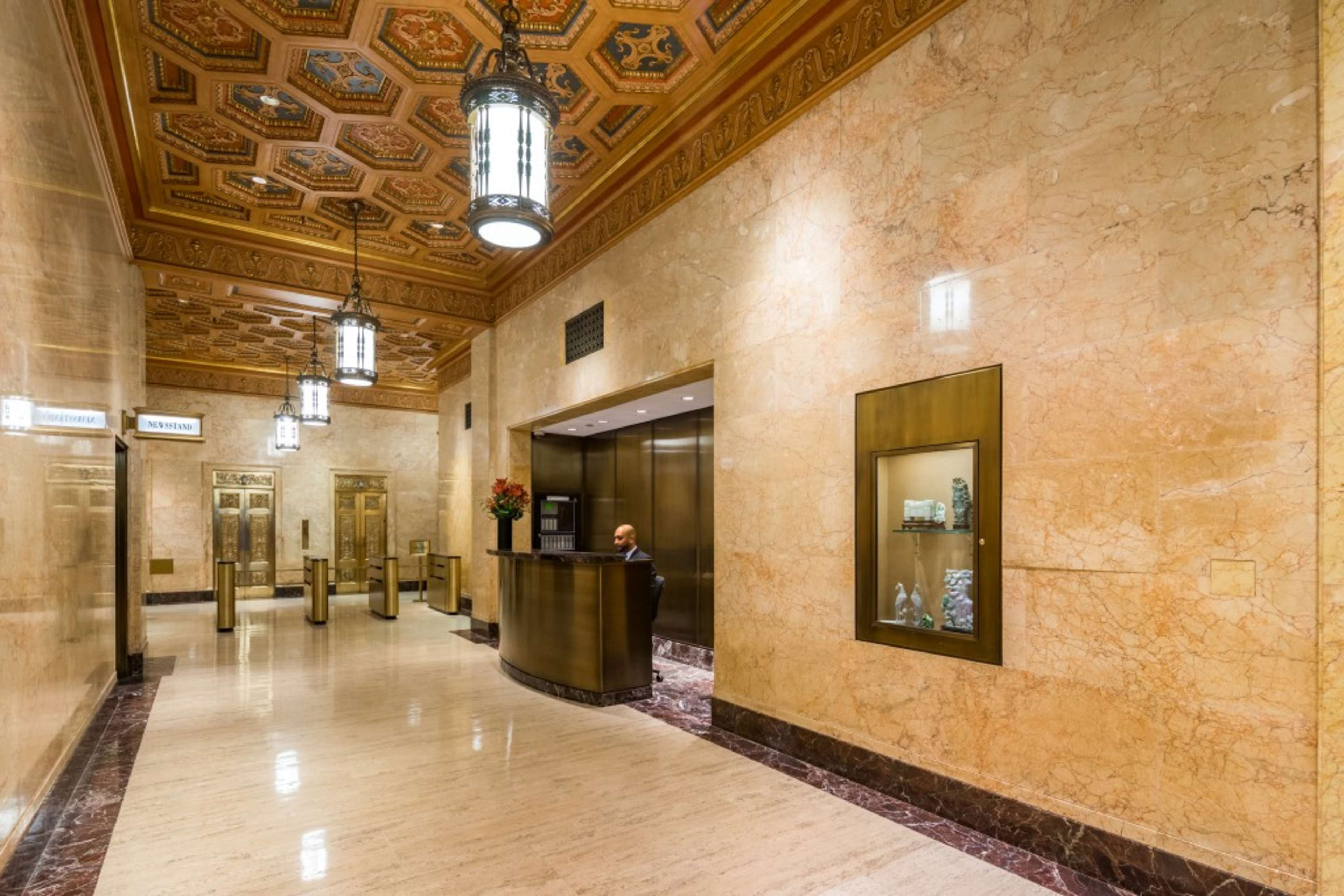 An elegant lobby features marble walls, a reception desk, and decorative lighting.