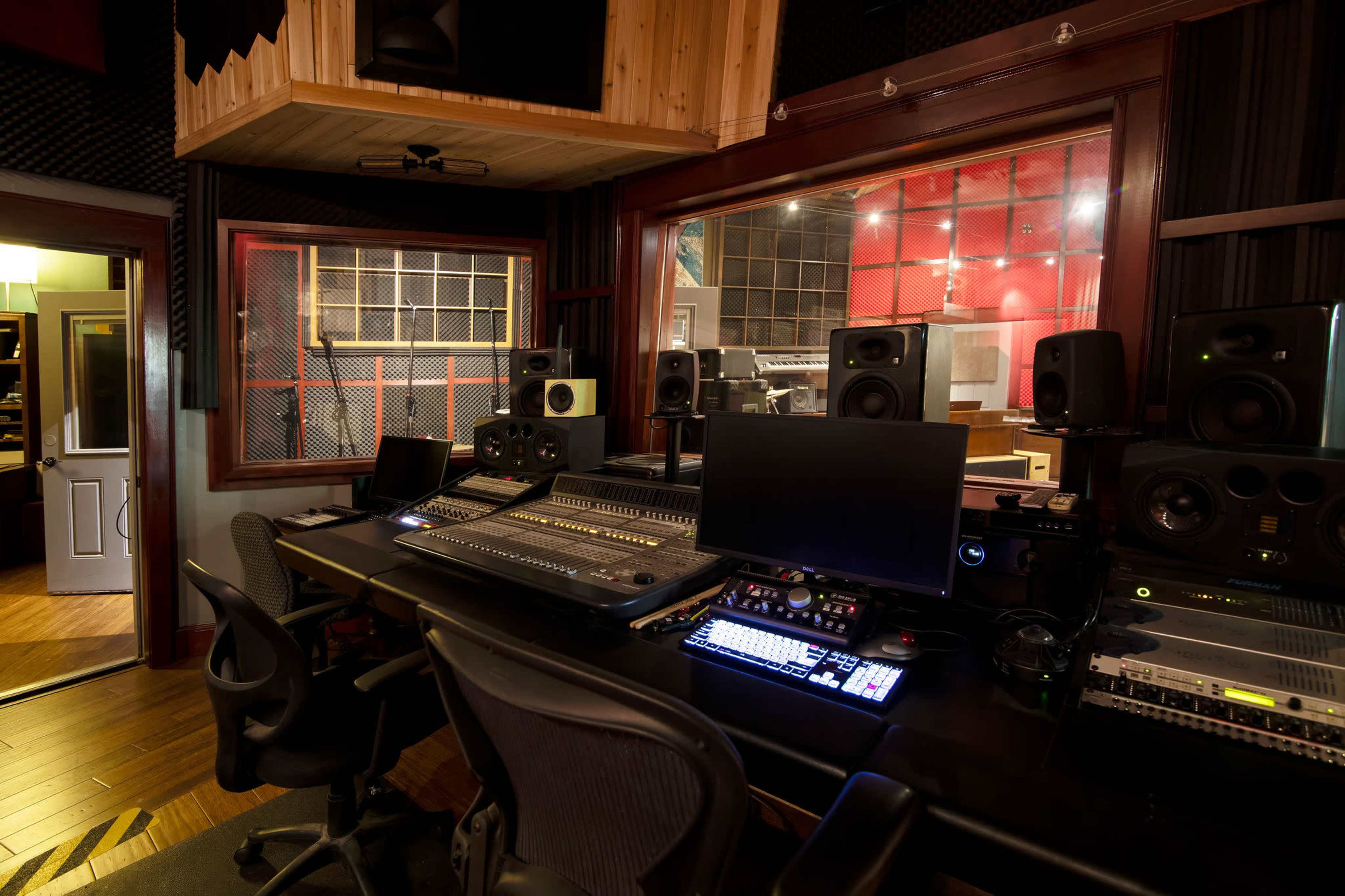 A recording studio equipped with a mixing console, speakers, and soundproofing panels.
