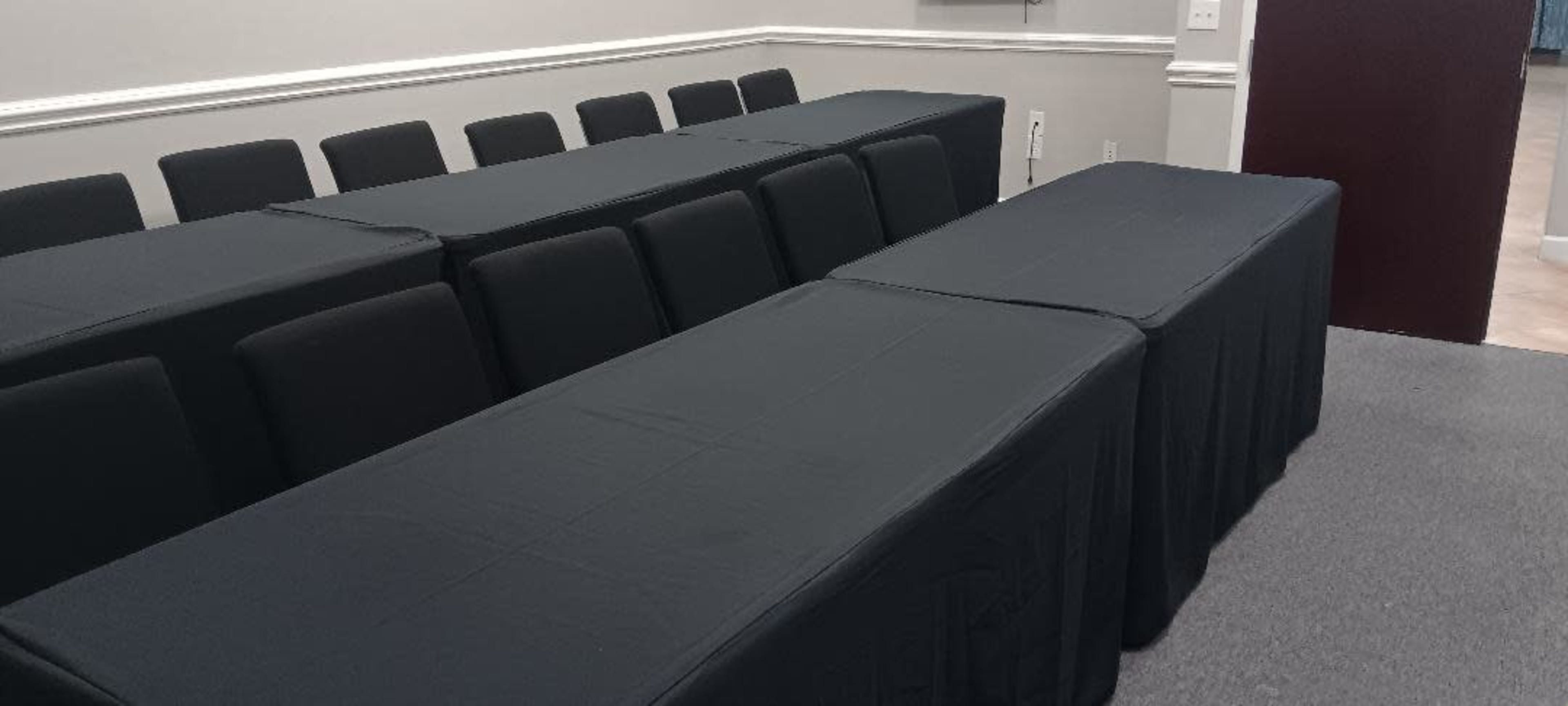 A room with two rows of black-covered tables set up in a meeting configuration.