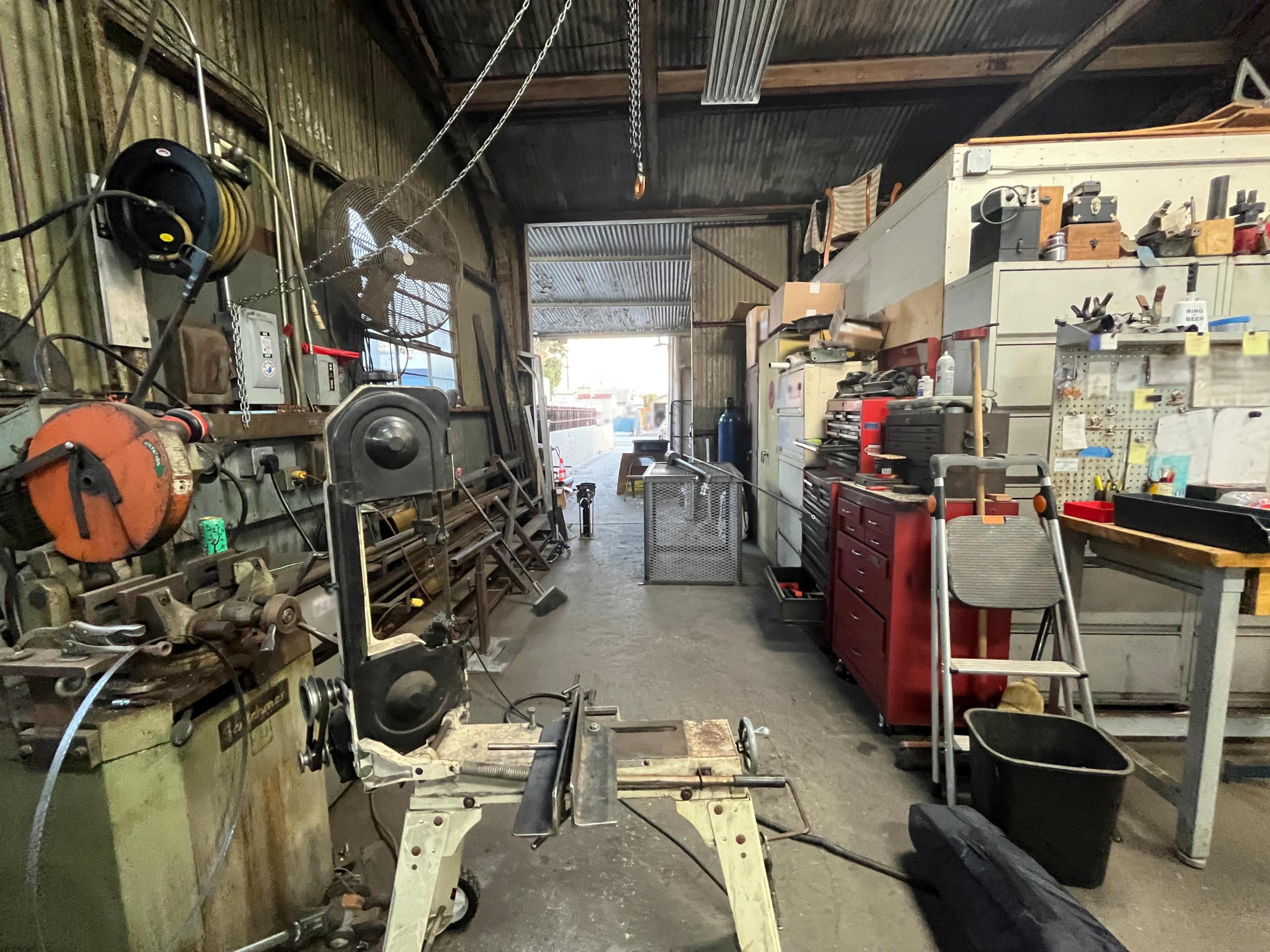 A workshop interior features various tools, a workbench, and organized storage cabinets along the walls.