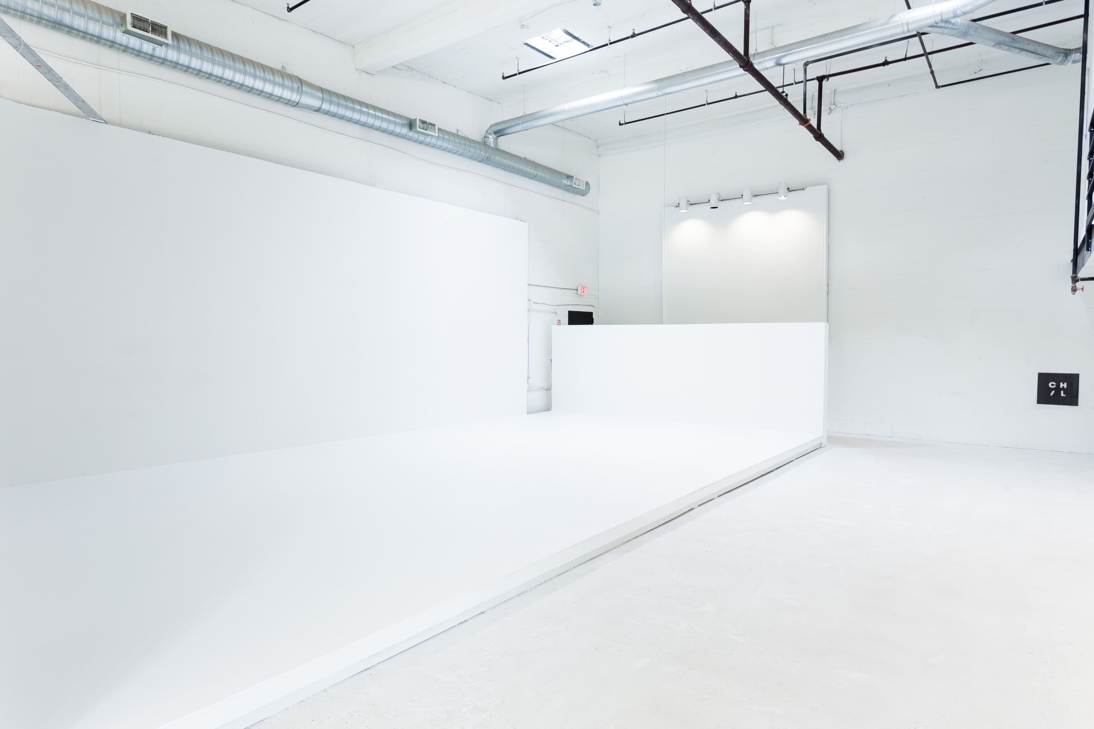 An empty, white studio space with minimalist design and bright lighting.