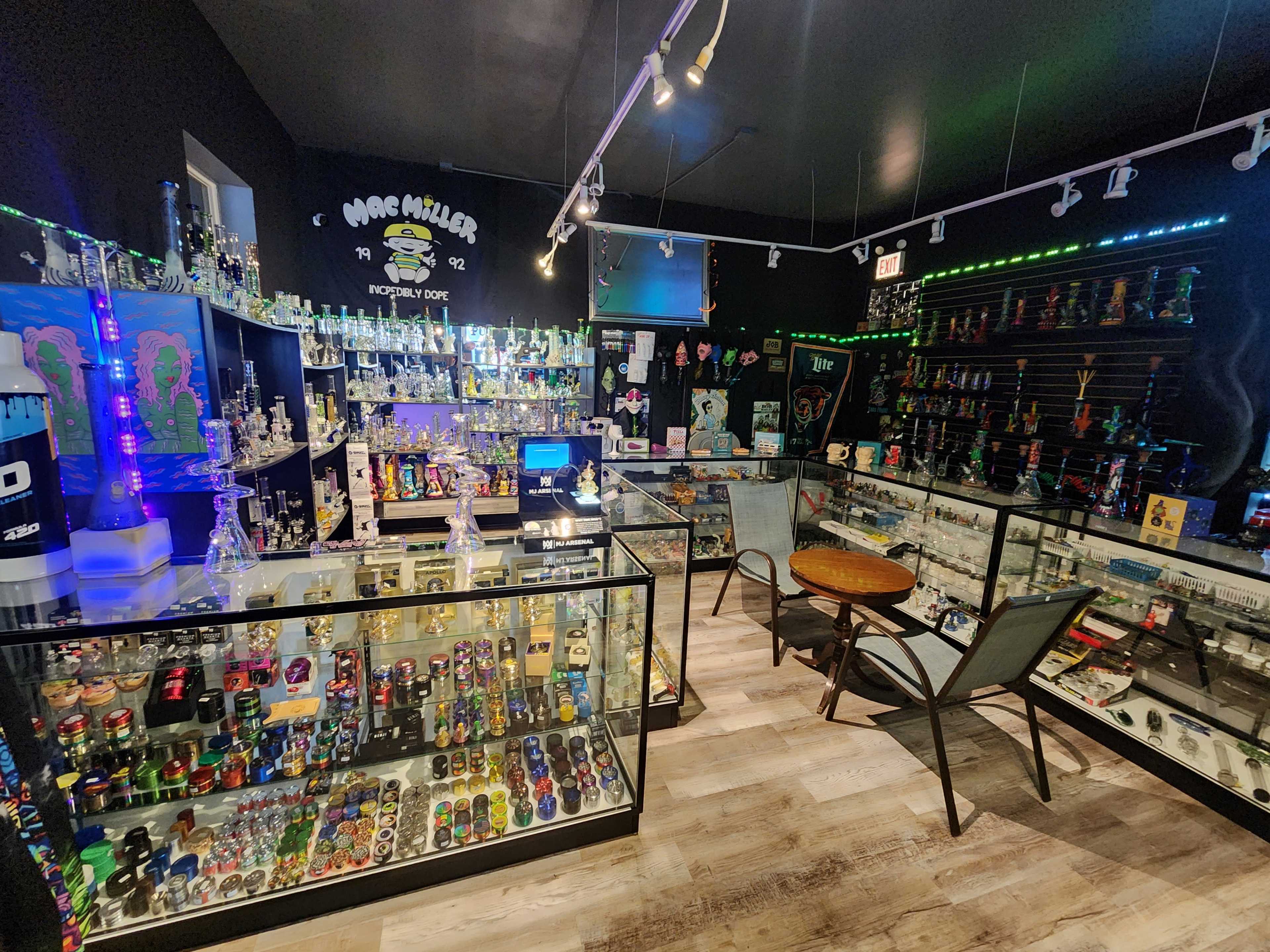The image shows a well-organized retail shop featuring a variety of glass smoking accessories and merchandise displayed in glass cases and on shelves.