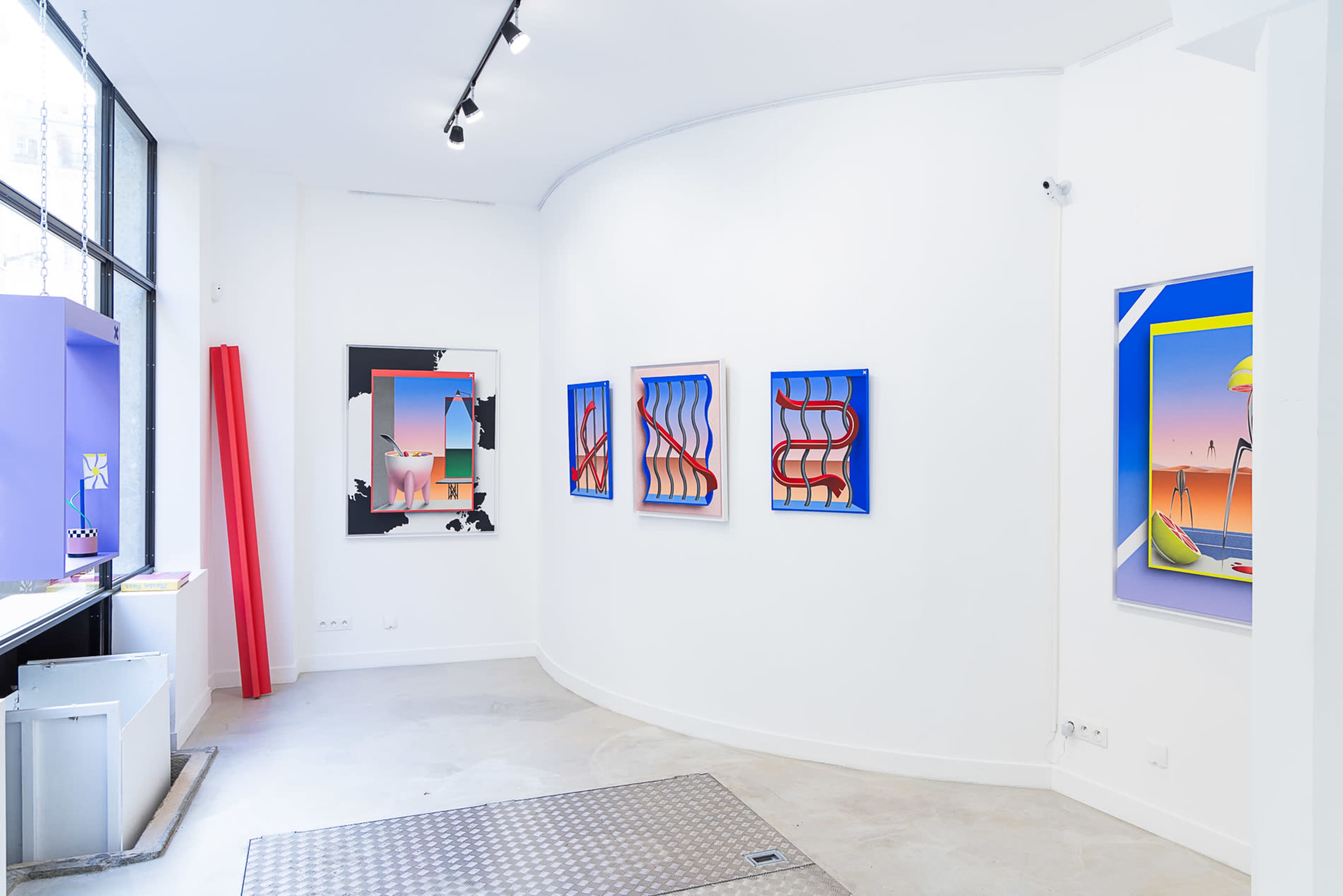 An art gallery with several colorful framed paintings on white walls, featuring a curved layout and a mix of modern design elements.