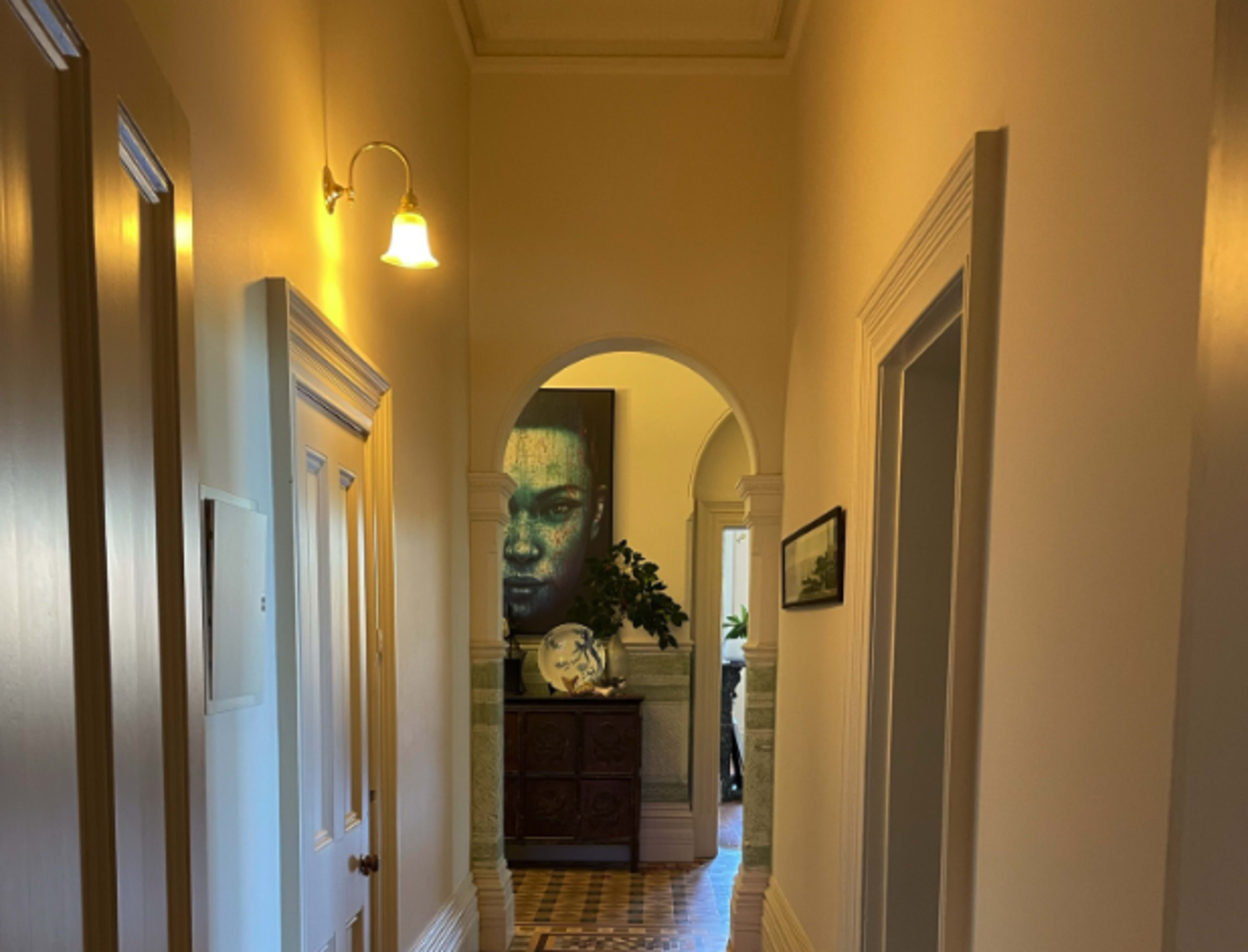 A hallway features light fixtures, wall art, and doorways leading to a living area.