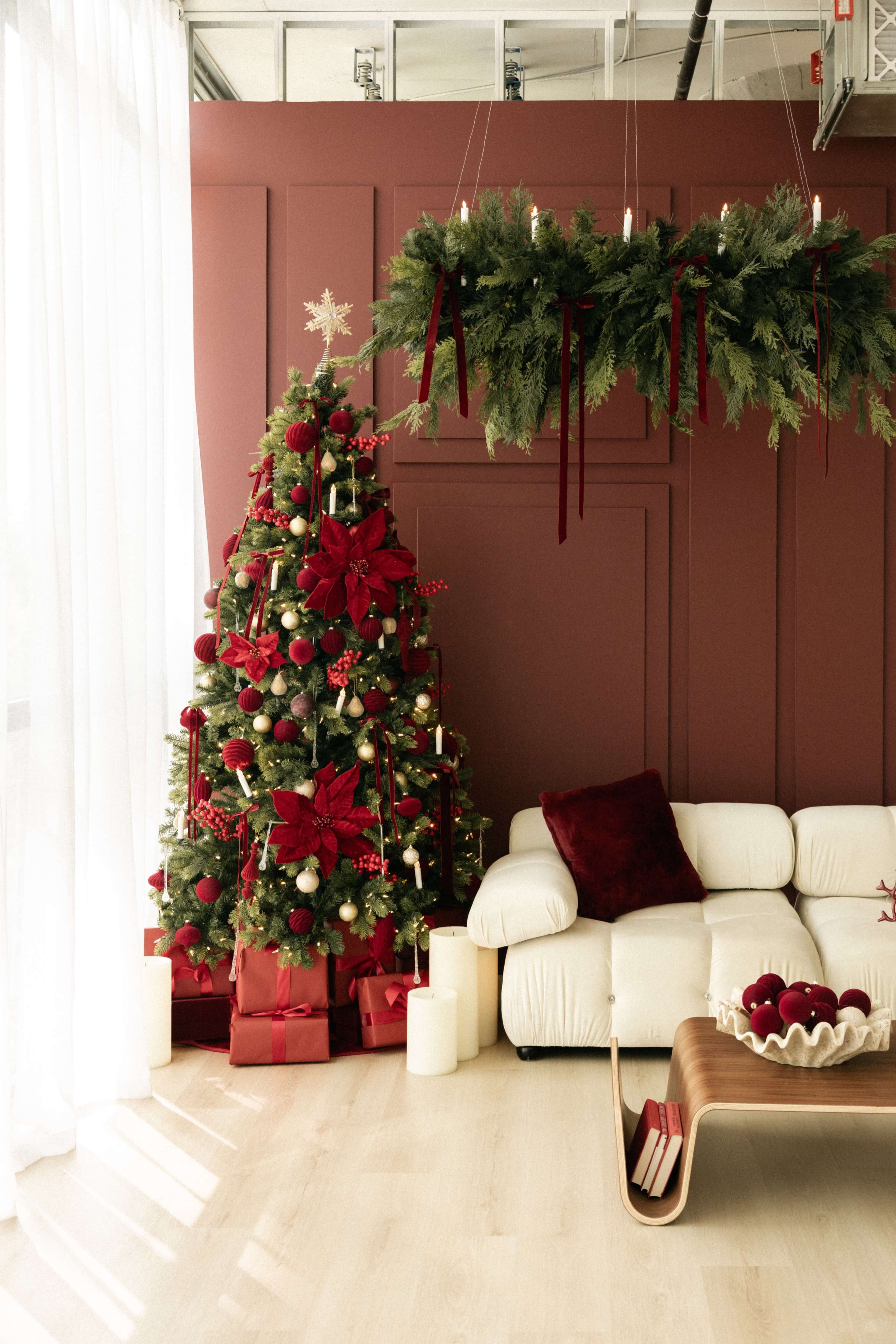 The image shows a living room decorated for Christmas, featuring a Christmas tree adorned with red bows and ornaments next to a white couch.