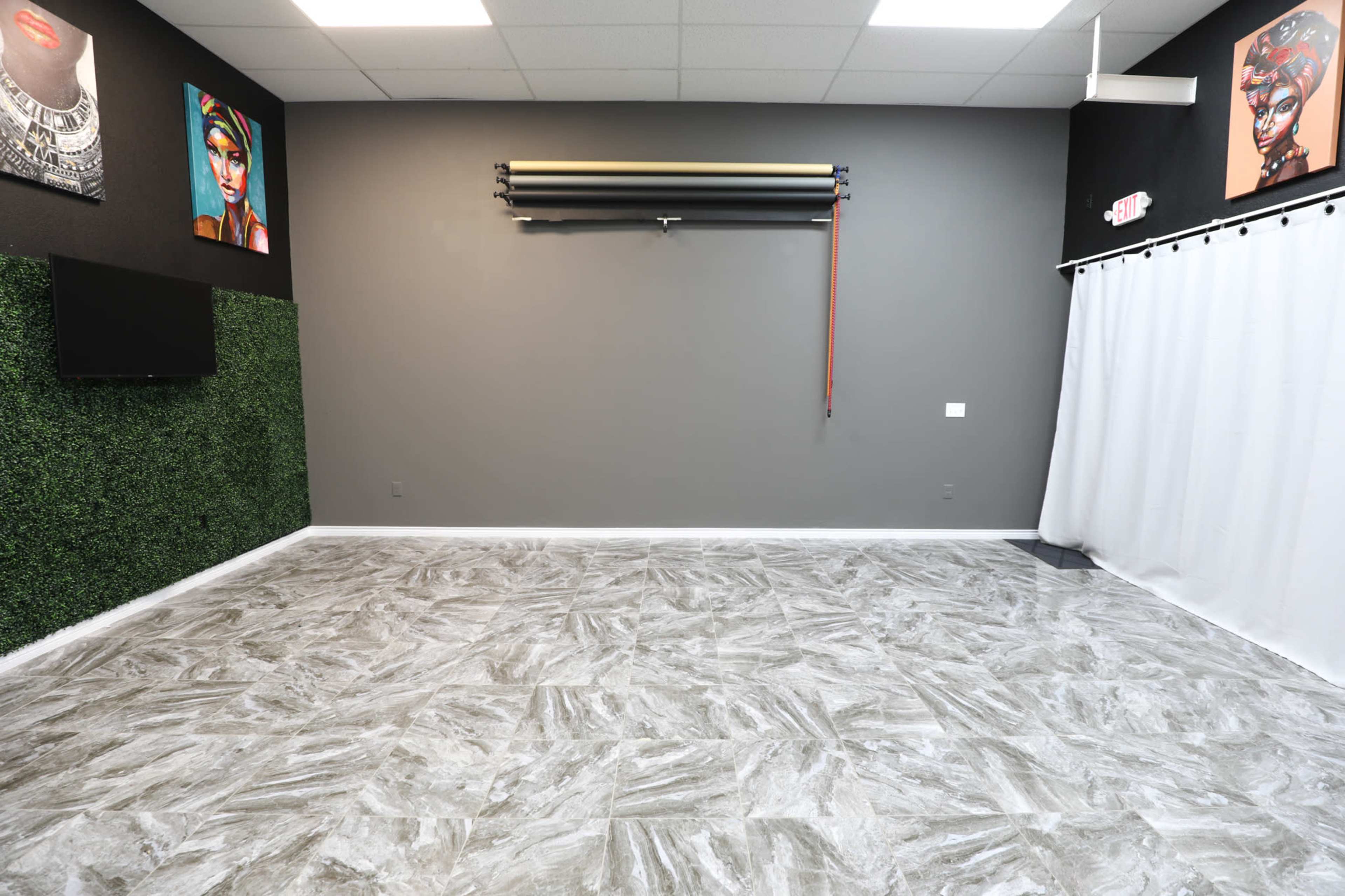 A spacious room with gray walls, decorative artwork, a green accent wall, and a textured floor.