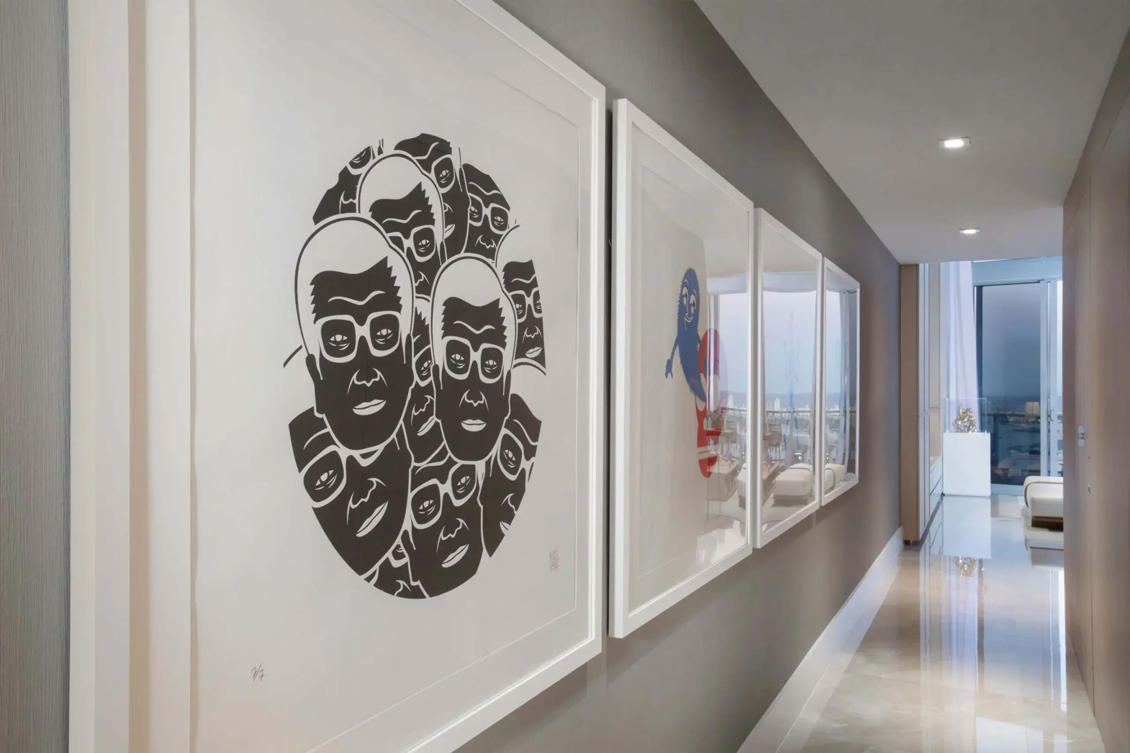 A hallway with framed artworks, including black-and-white illustrations of faces and colorful pieces on the adjacent wall.