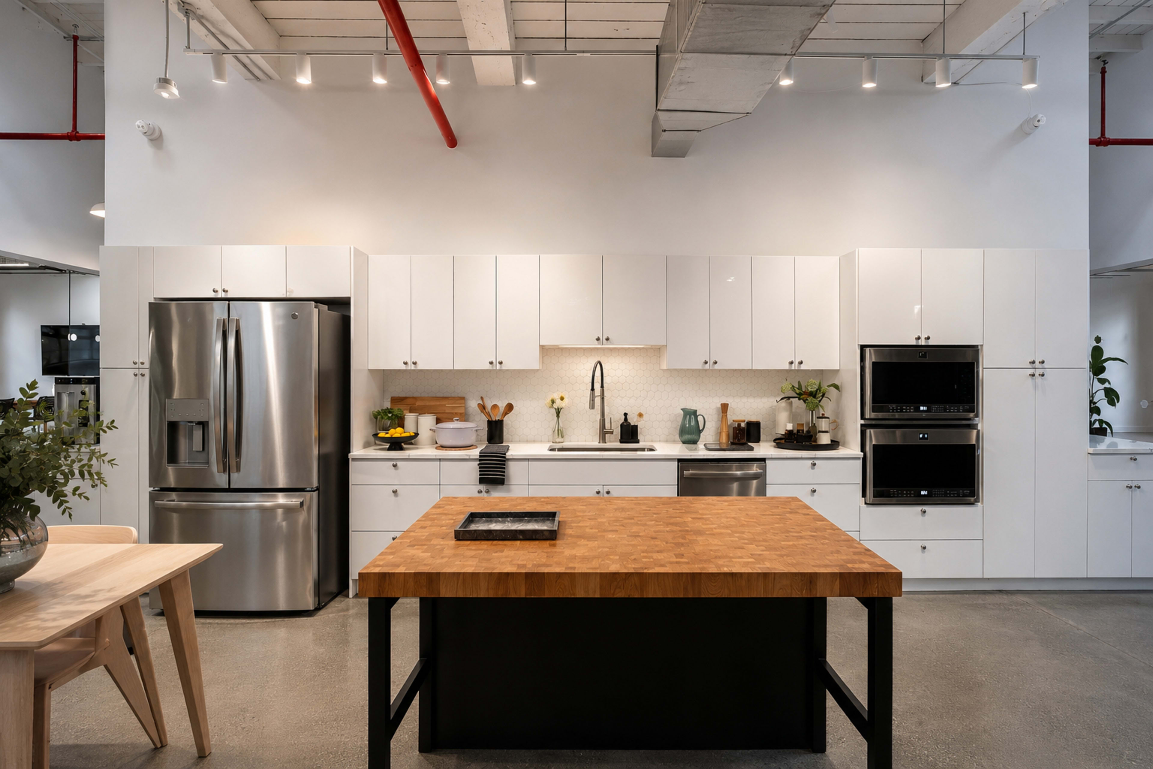 The image shows a modern kitchen featuring white cabinetry, a stainless steel refrigerator, and a central wooden island with a black base.
