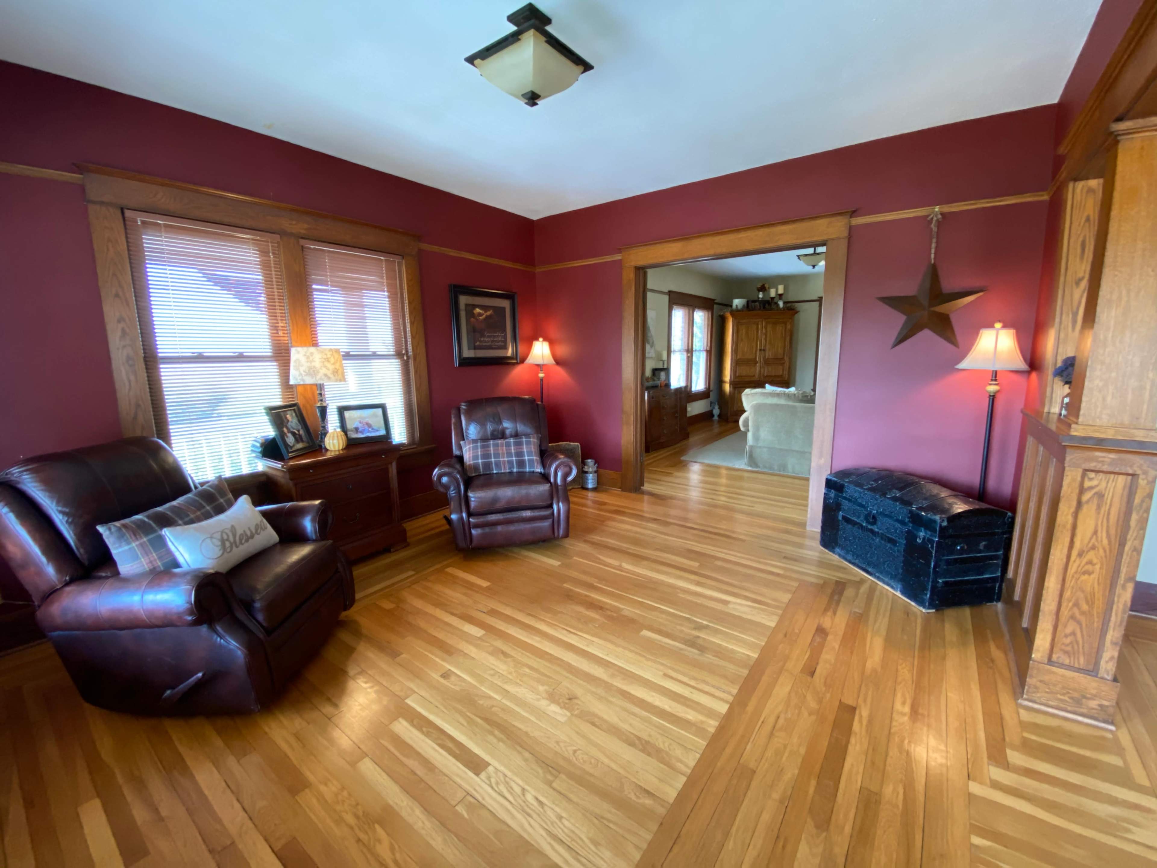 The image shows a living room with two brown leather recliners, wooden accents, and a doorway leading to another room.