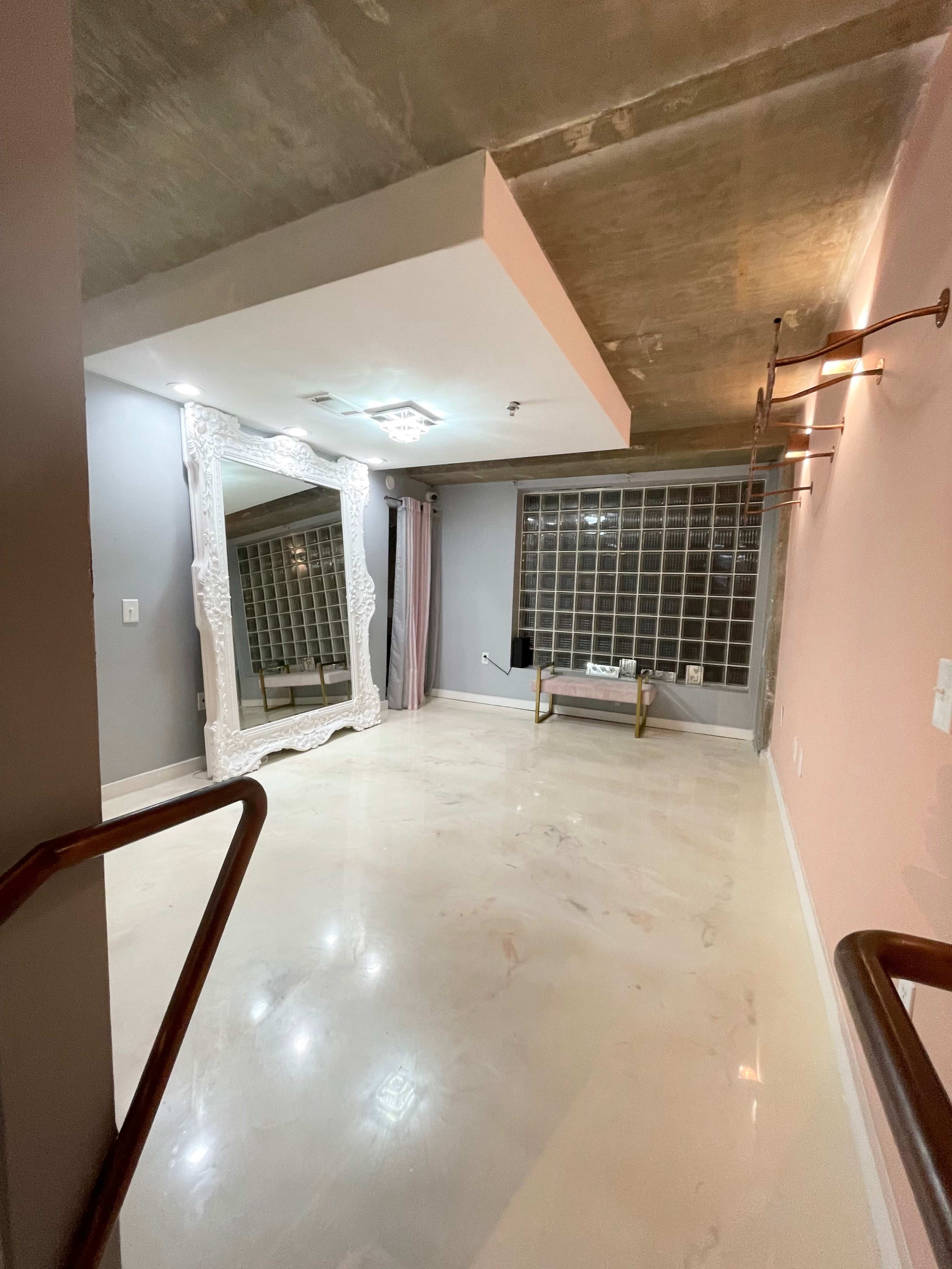 The room features a large ornate mirror, a glass block window, and a smooth, light-colored floor.