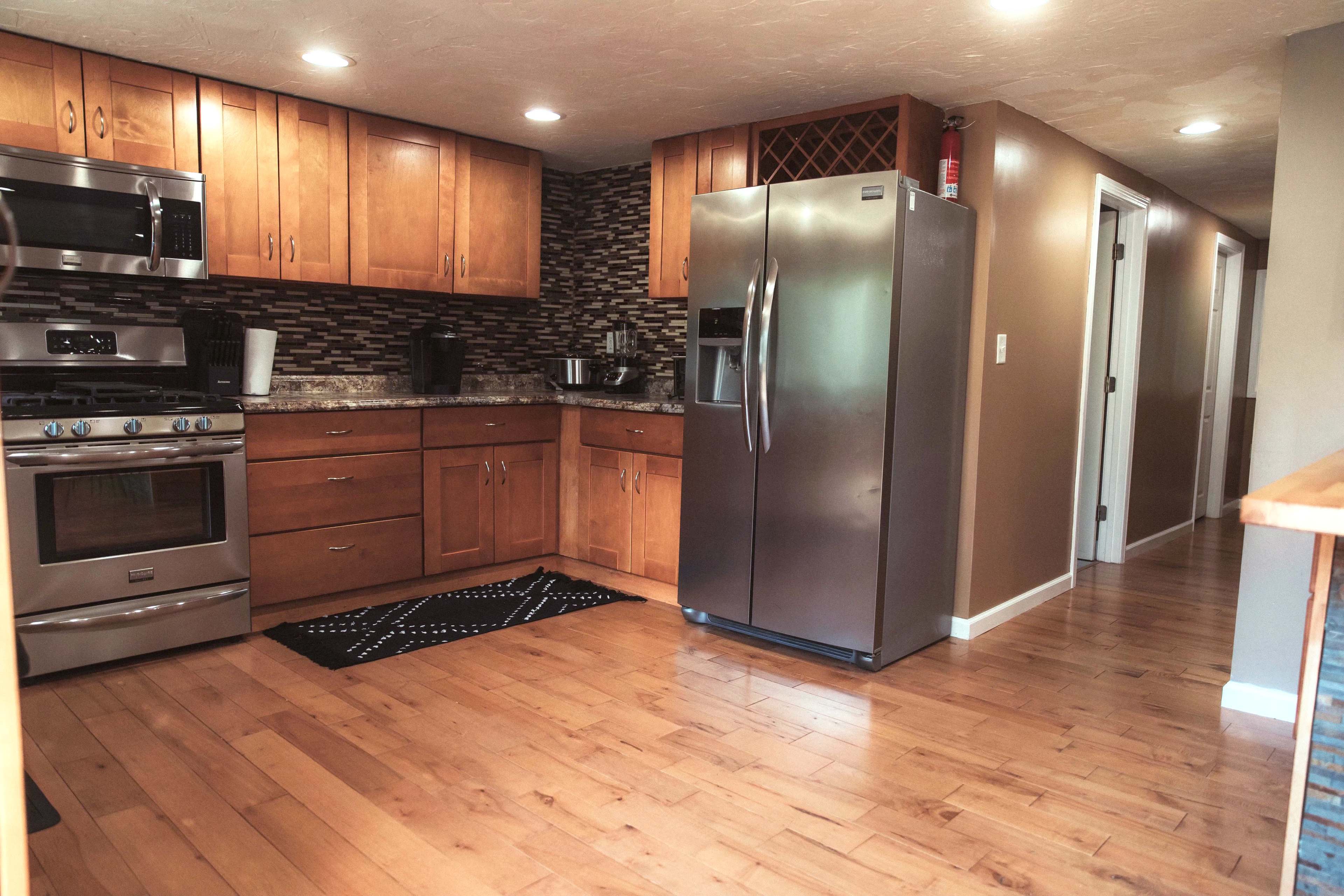 A modern kitchen with wooden cabinets, stainless steel appliances, and a tiled backsplash.