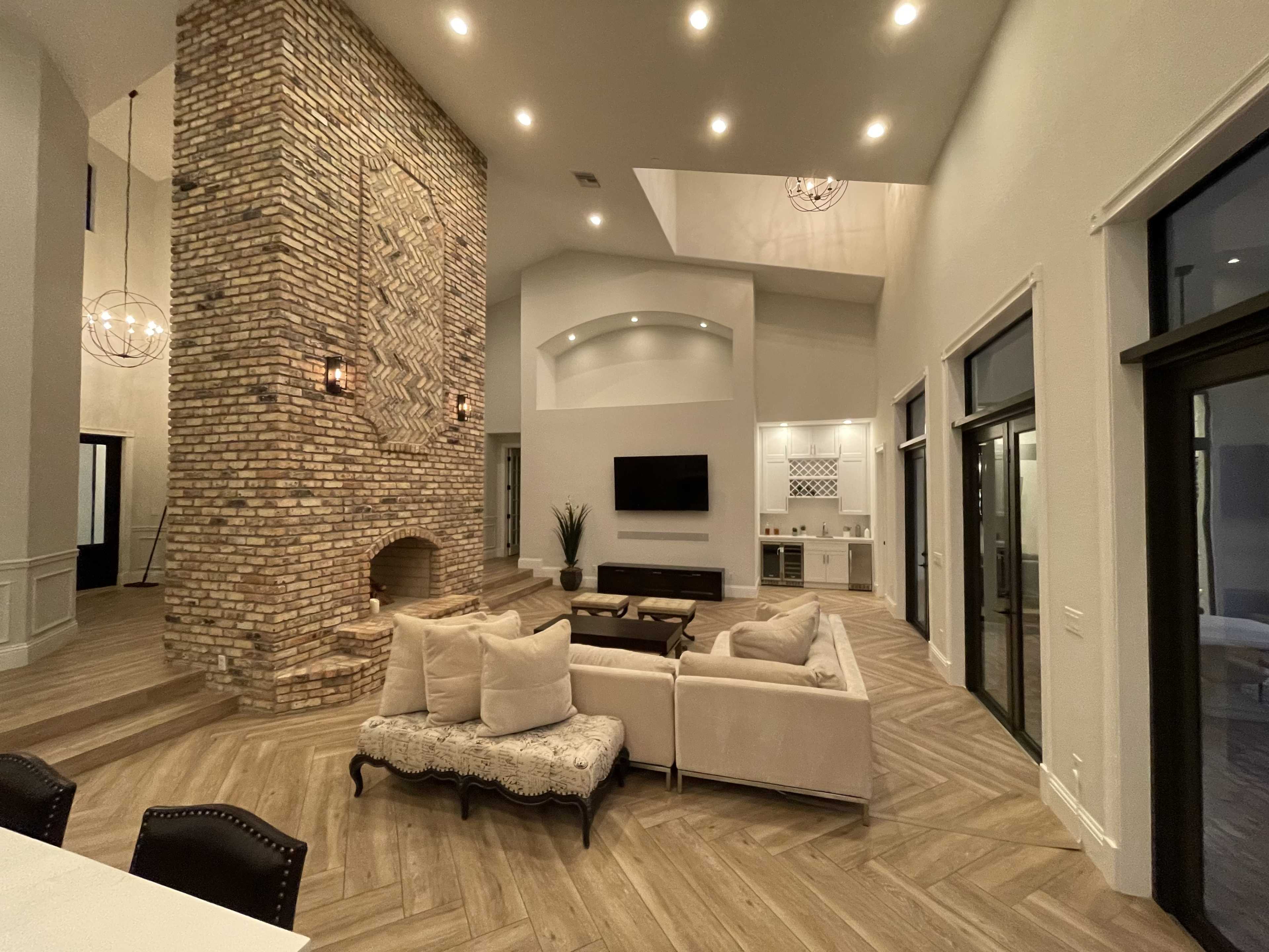 A spacious living area with a tall brick feature wall, modern furniture, and large windows providing ample natural light.