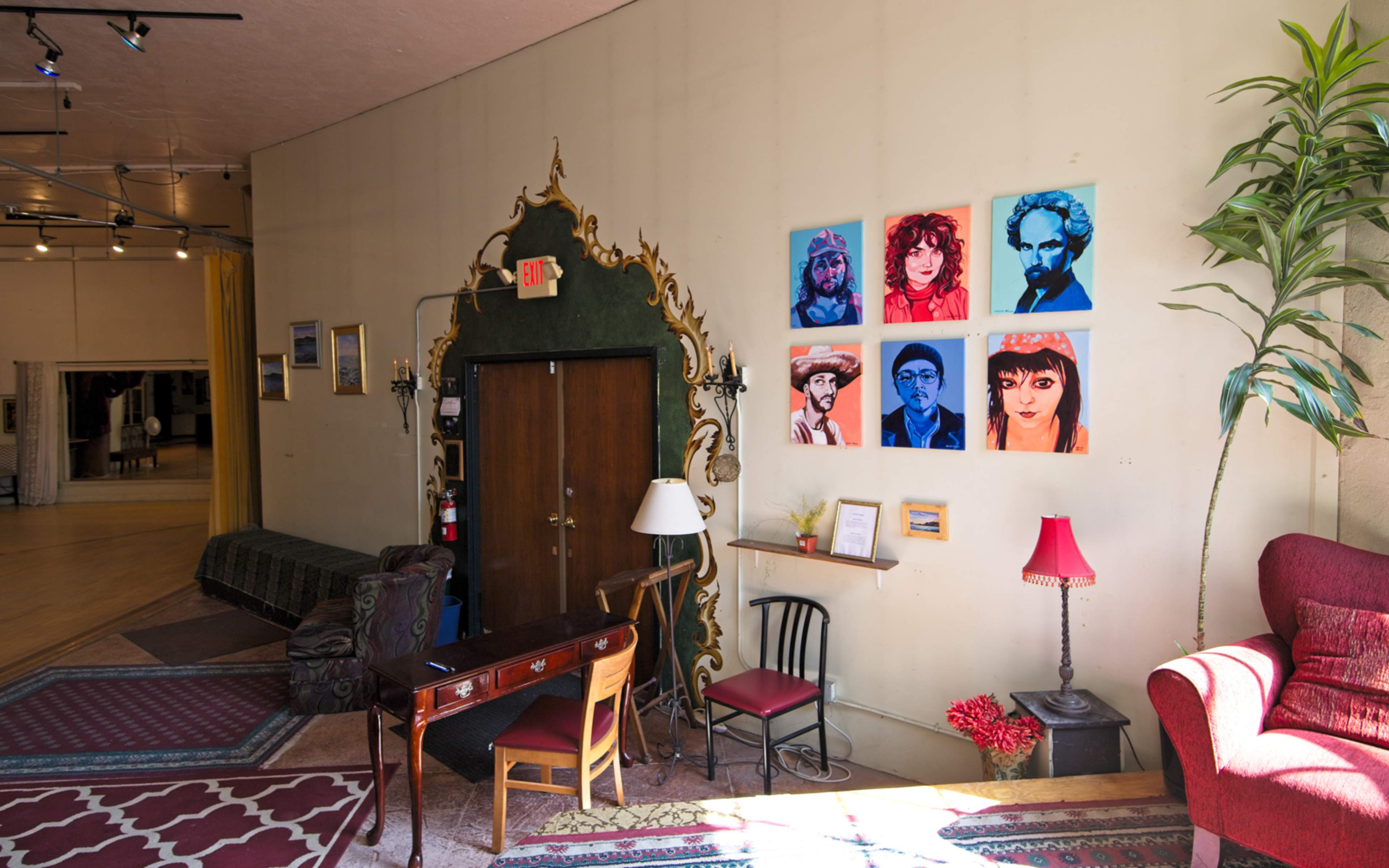 A spacious interior with a decorative entrance, a seating area, and a wall featuring colorful portraits.