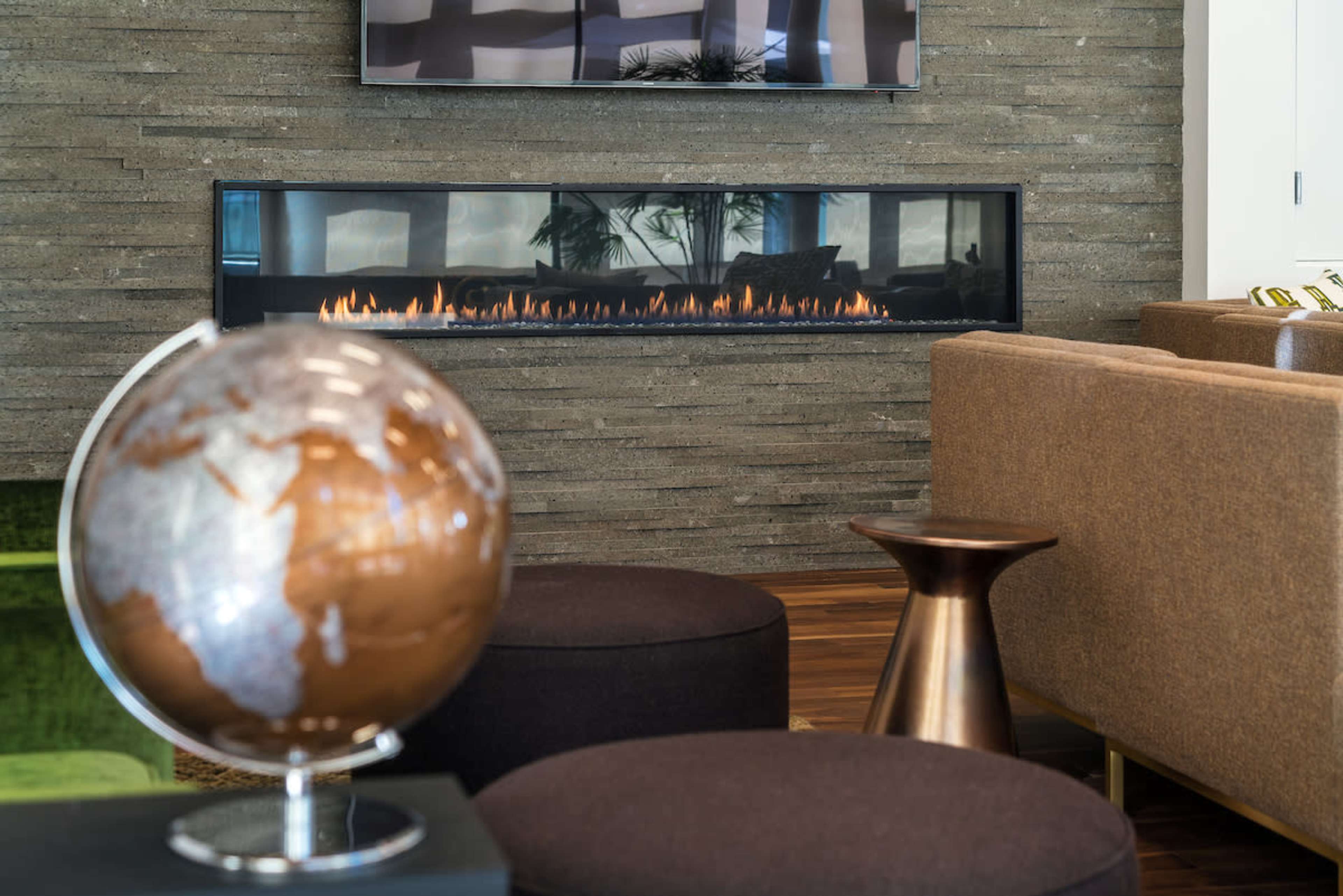 A modern living area with a wall-mounted fireplace, a globe on a stand, and contemporary seating.
