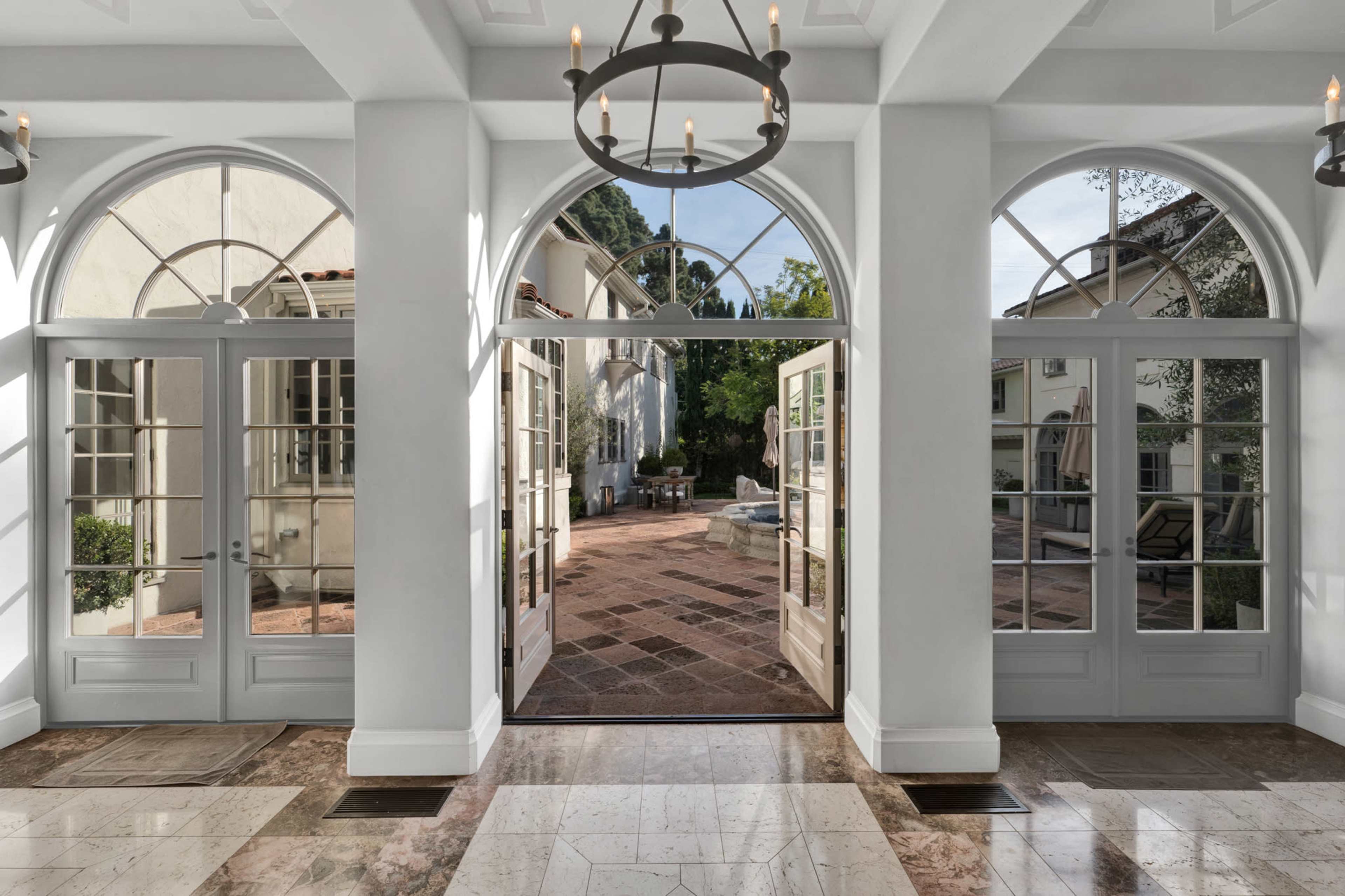The entrance features arched doorways that open to a tiled courtyard with greenery and seating areas.