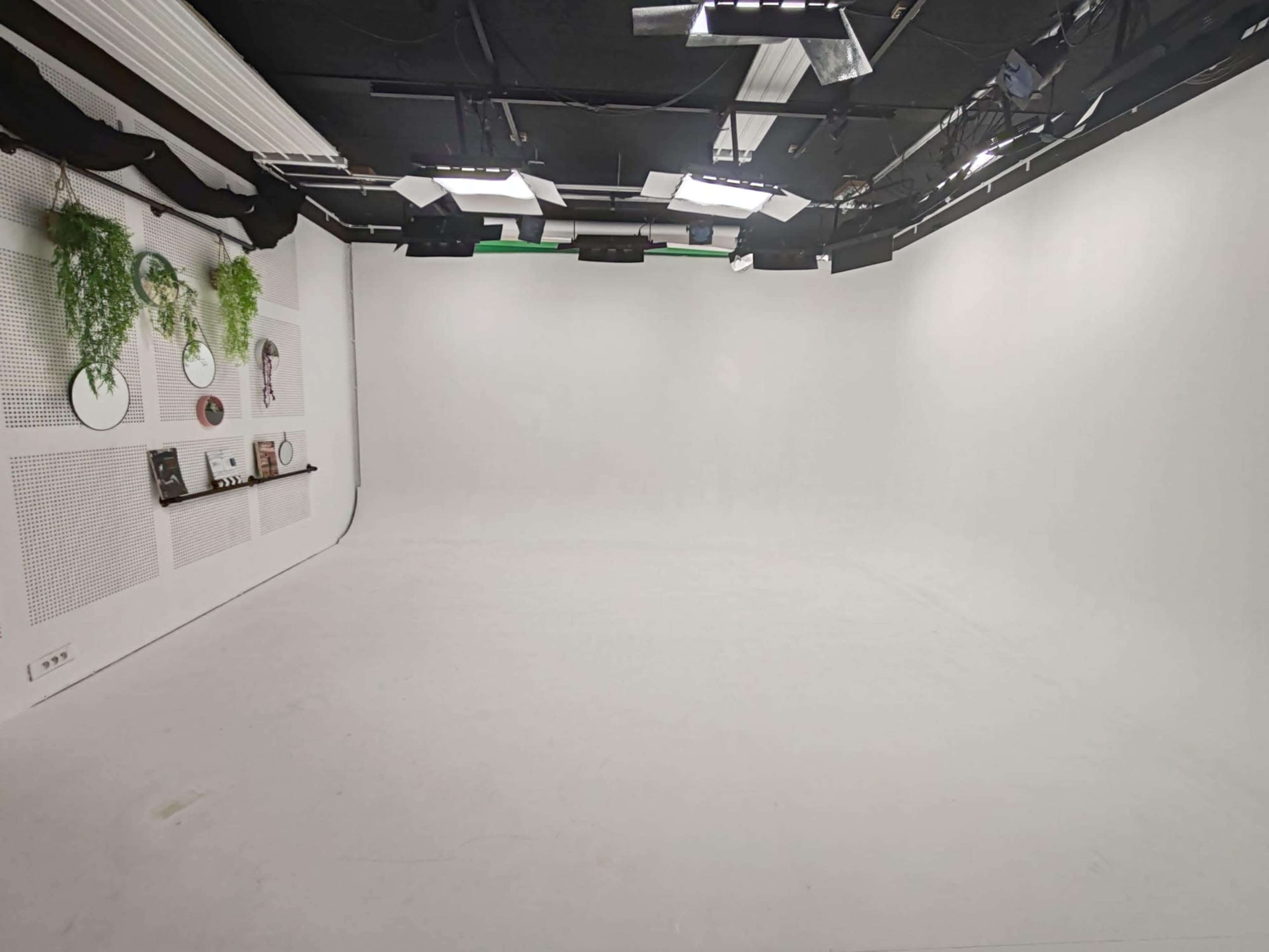 The image shows a spacious, empty studio with white walls, a smooth floor, and soft lighting.