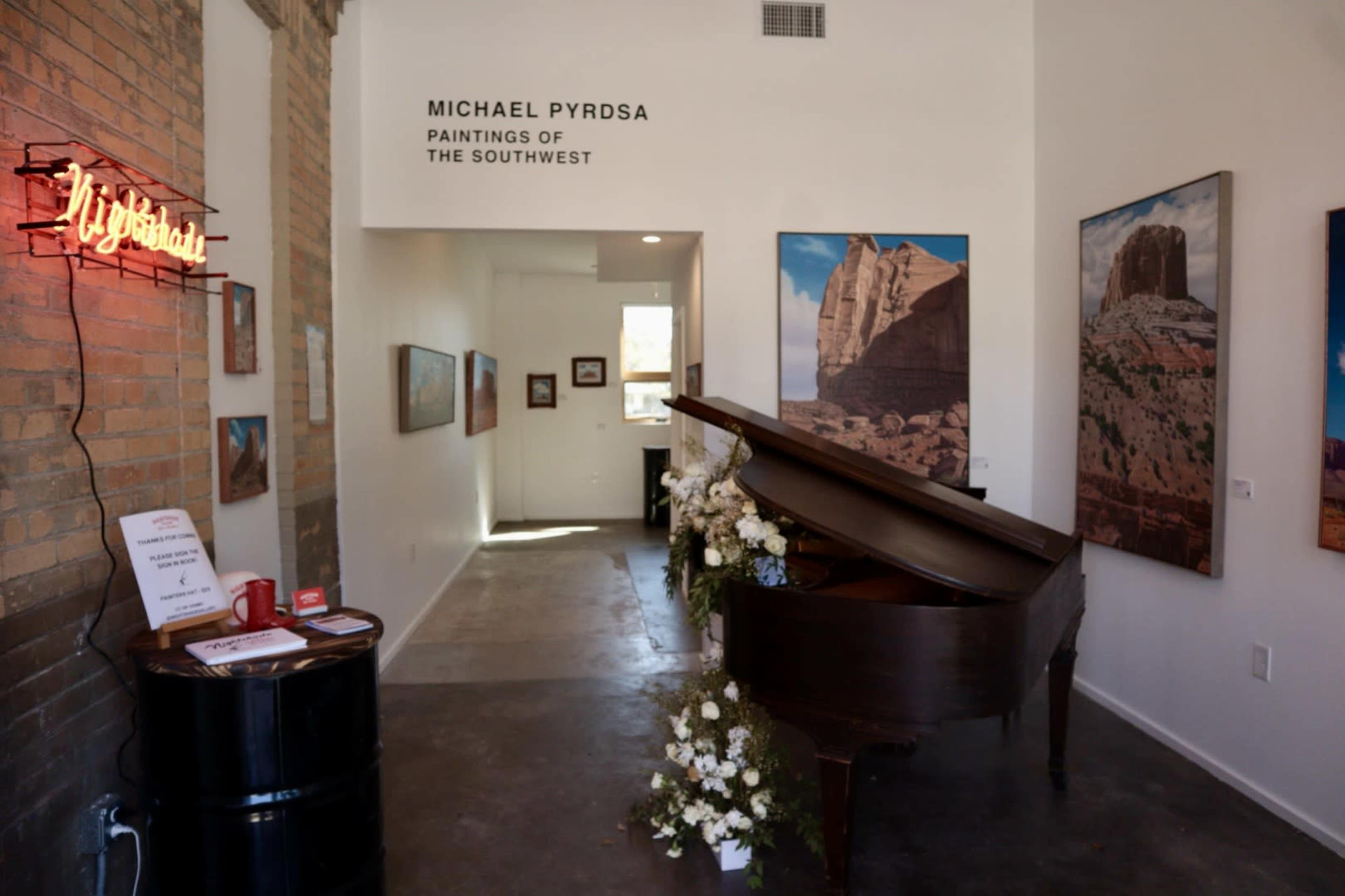 The image shows an art gallery entrance featuring a grand piano, paintings on the walls, and a neon sign that reads "Mysterious."