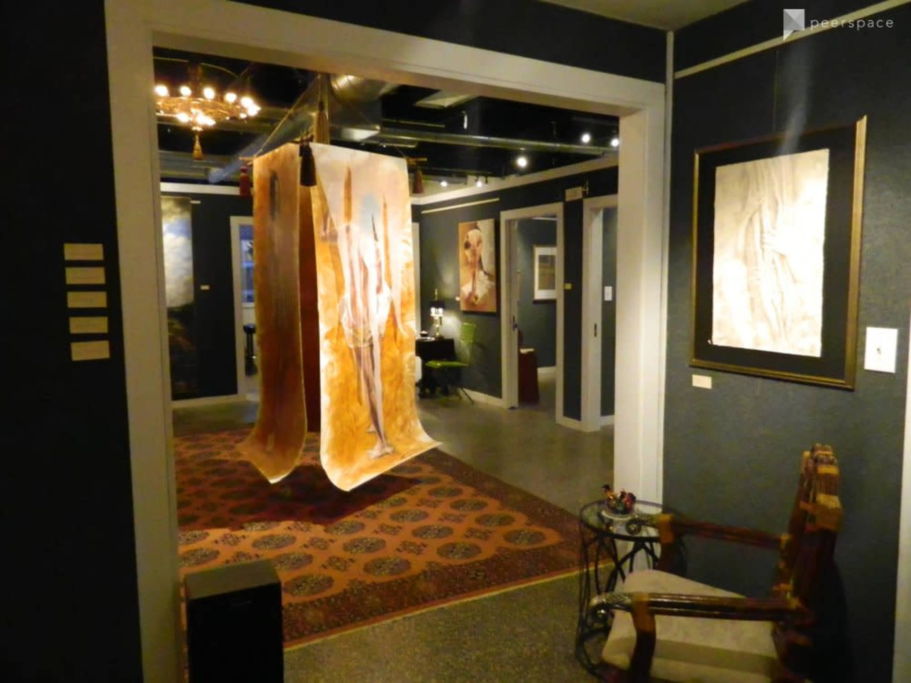 An art gallery entrance featuring a large translucent hanging installation and various artworks displayed on the walls.