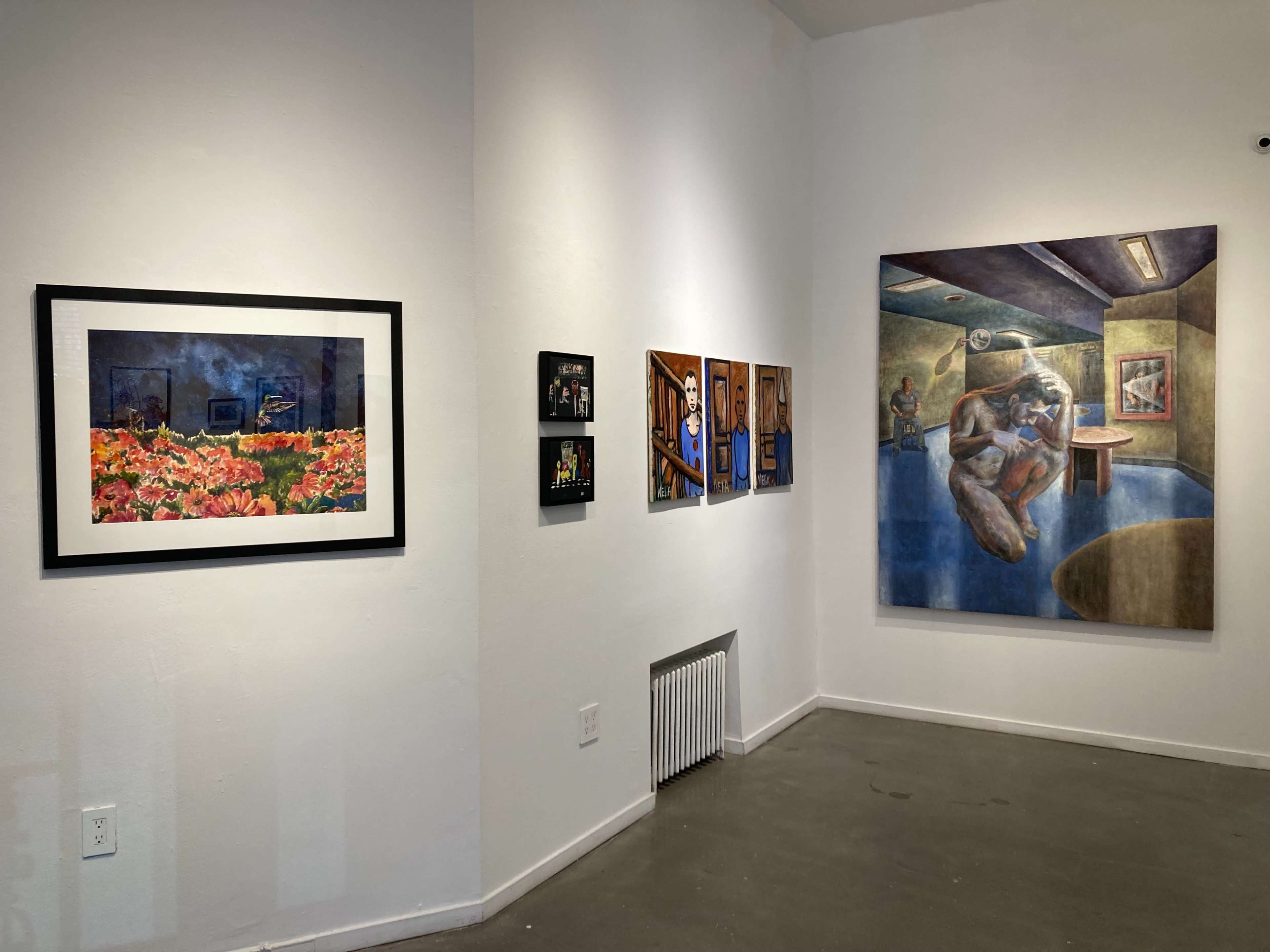 The image shows an art gallery wall displaying a variety of framed artworks, including photographs and paintings.