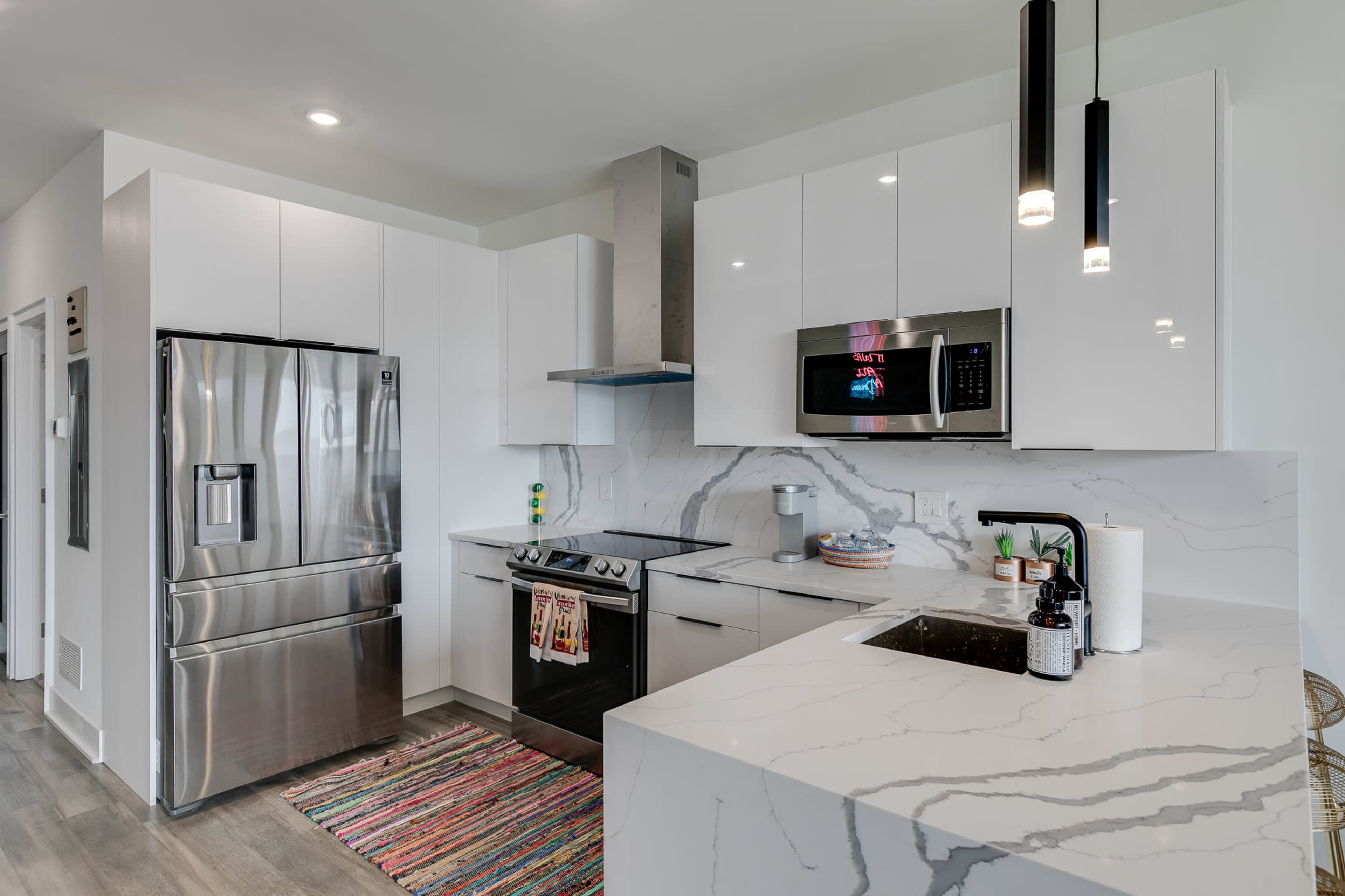 A modern kitchen with white cabinetry, stainless steel appliances, and a marble countertop.
