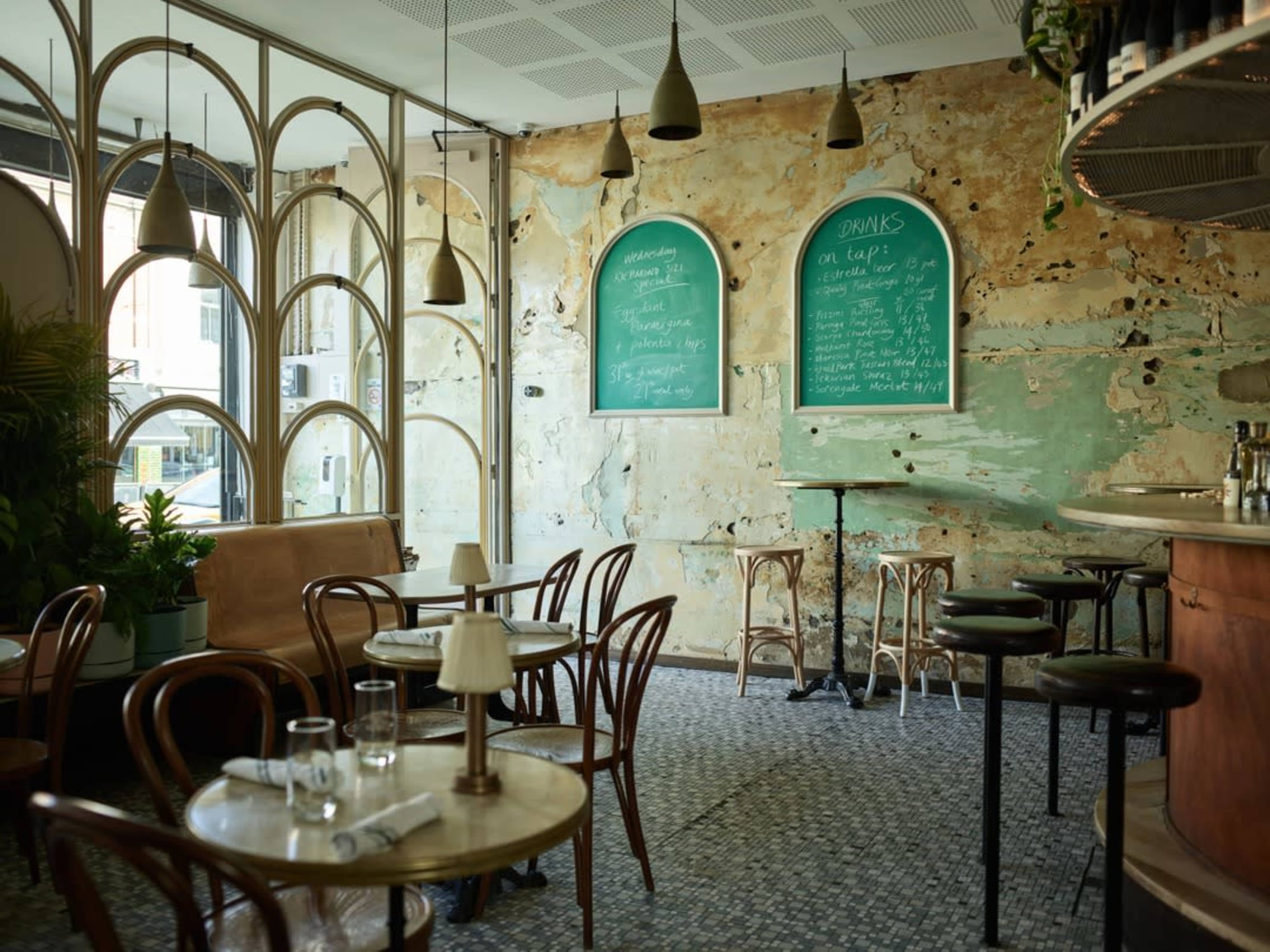 A cozy café with rustic décor, featuring wooden tables, a bar, and chalkboard menus on the walls.