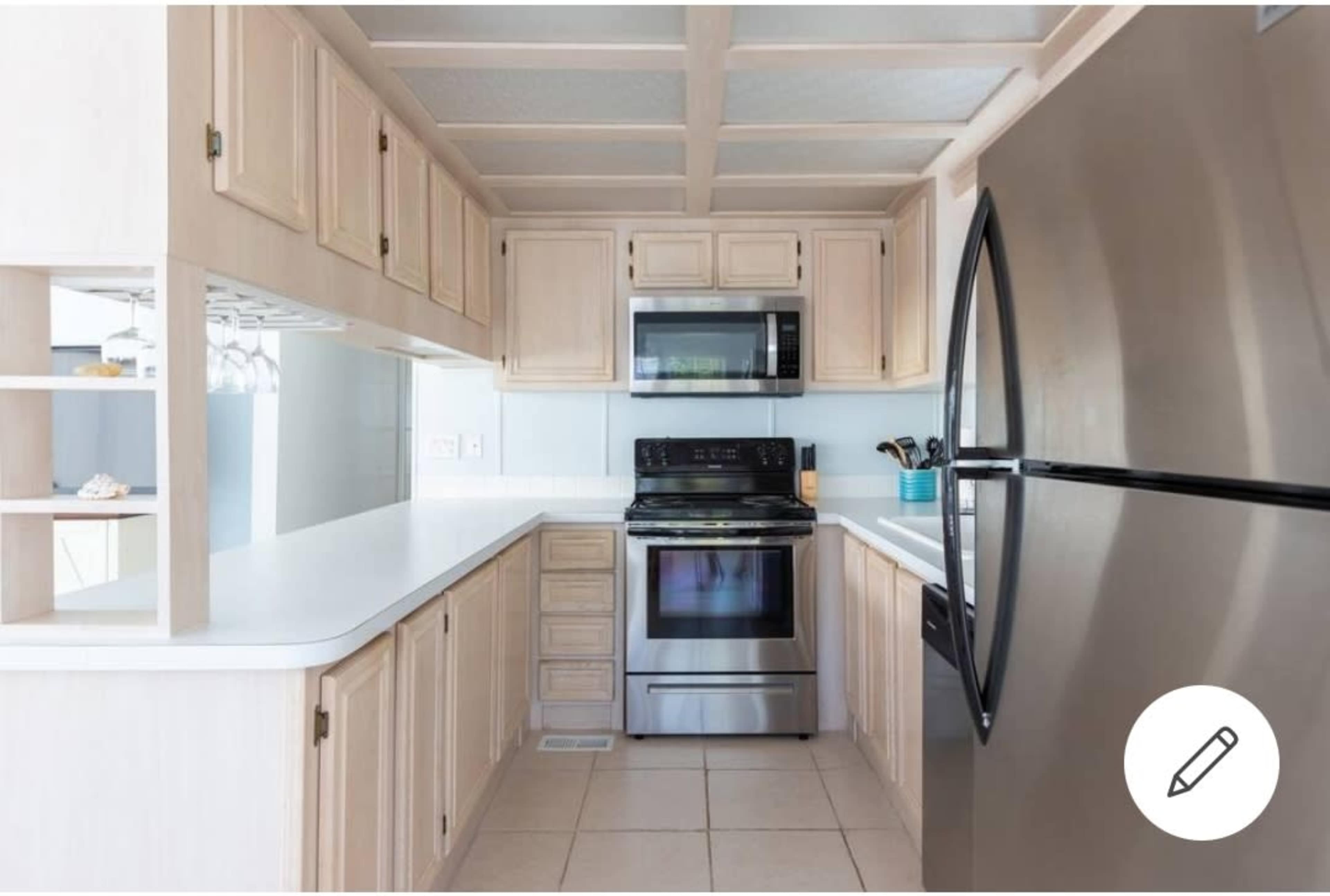 A kitchen with light wood cabinets, stainless steel appliances, and a white countertop.