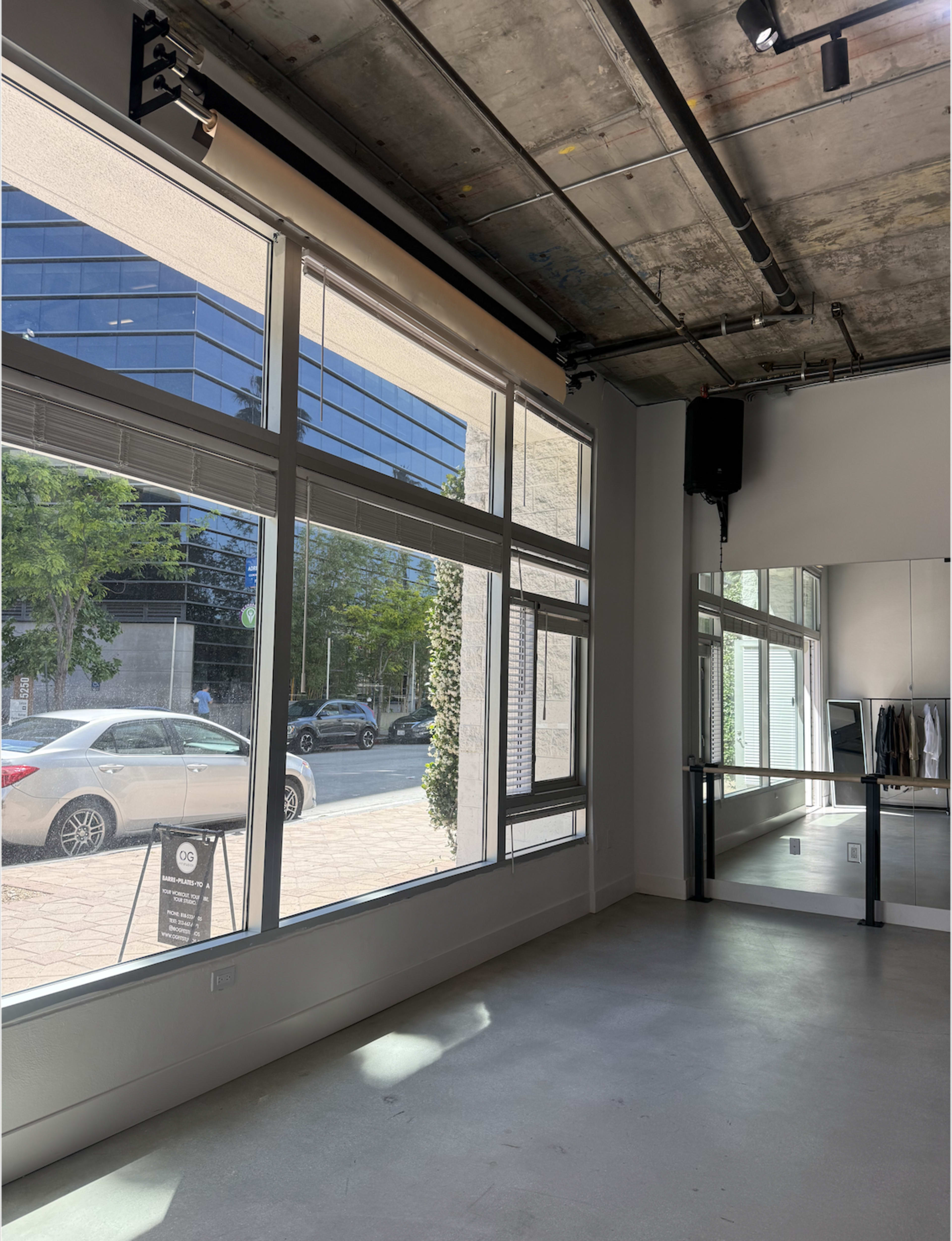The image depicts a modern interior space with large windows, showcasing a street view and a mirror along one wall.