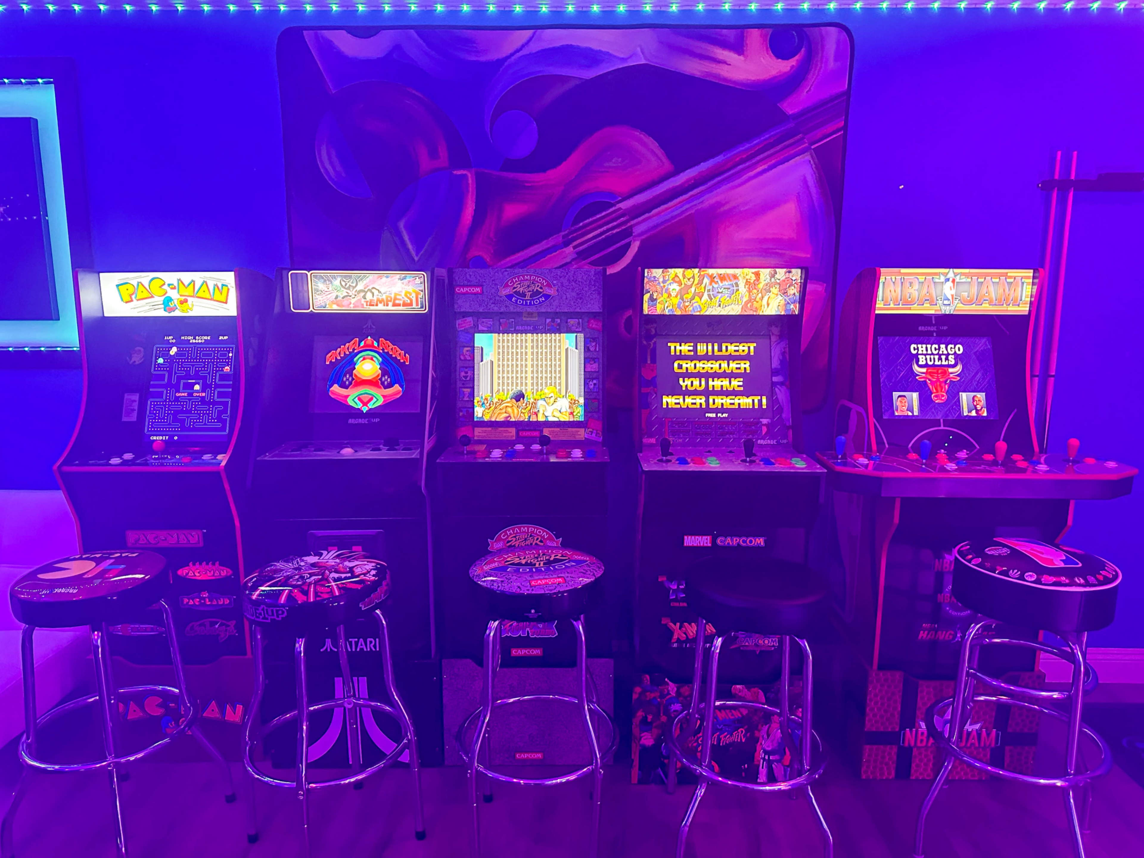 The image features a row of retro arcade machines illuminated by colorful lights in a dimly lit room.