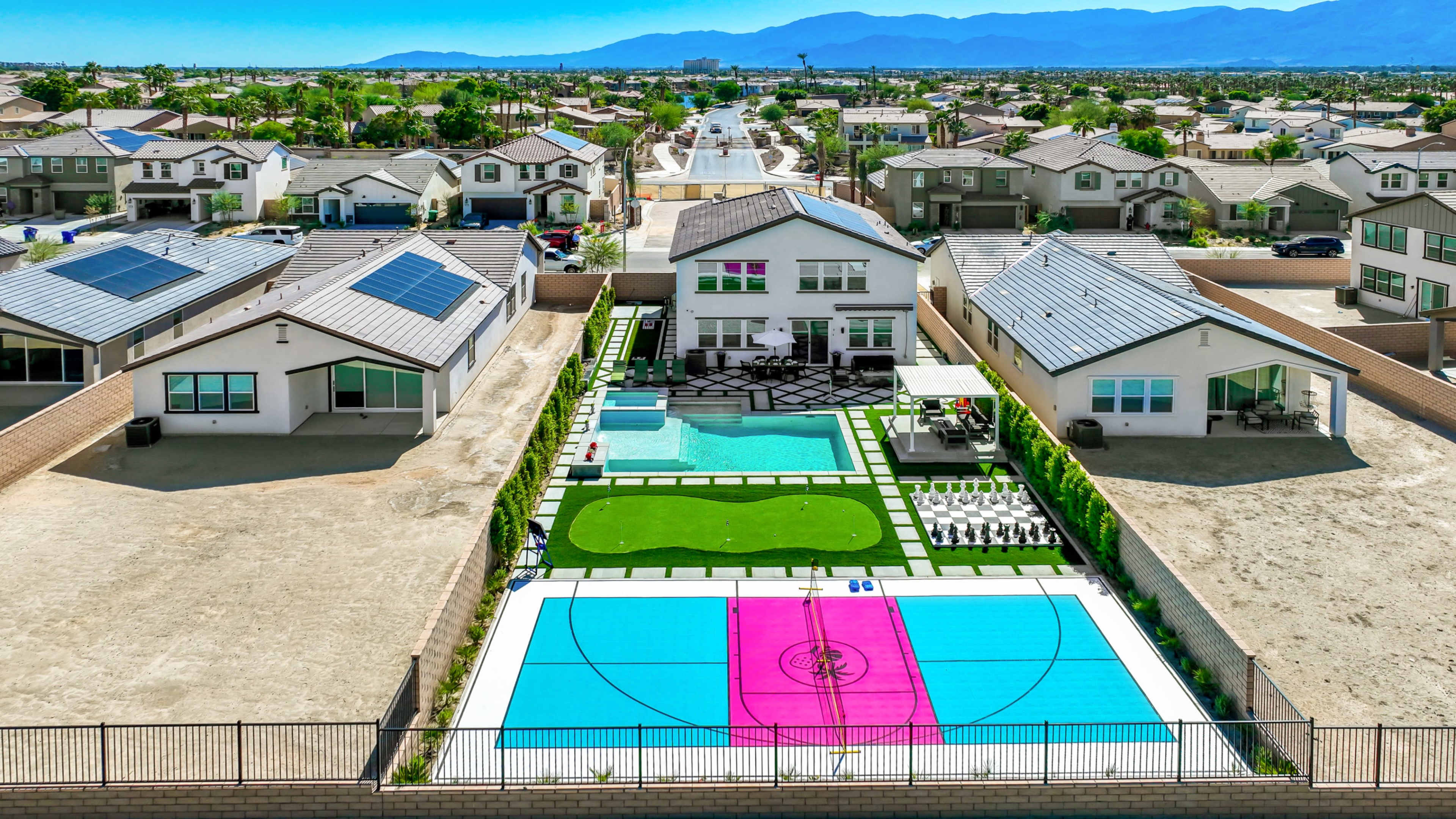 The image shows a backyard with a swimming pool, a basketball court, and several houses visible in the background.
