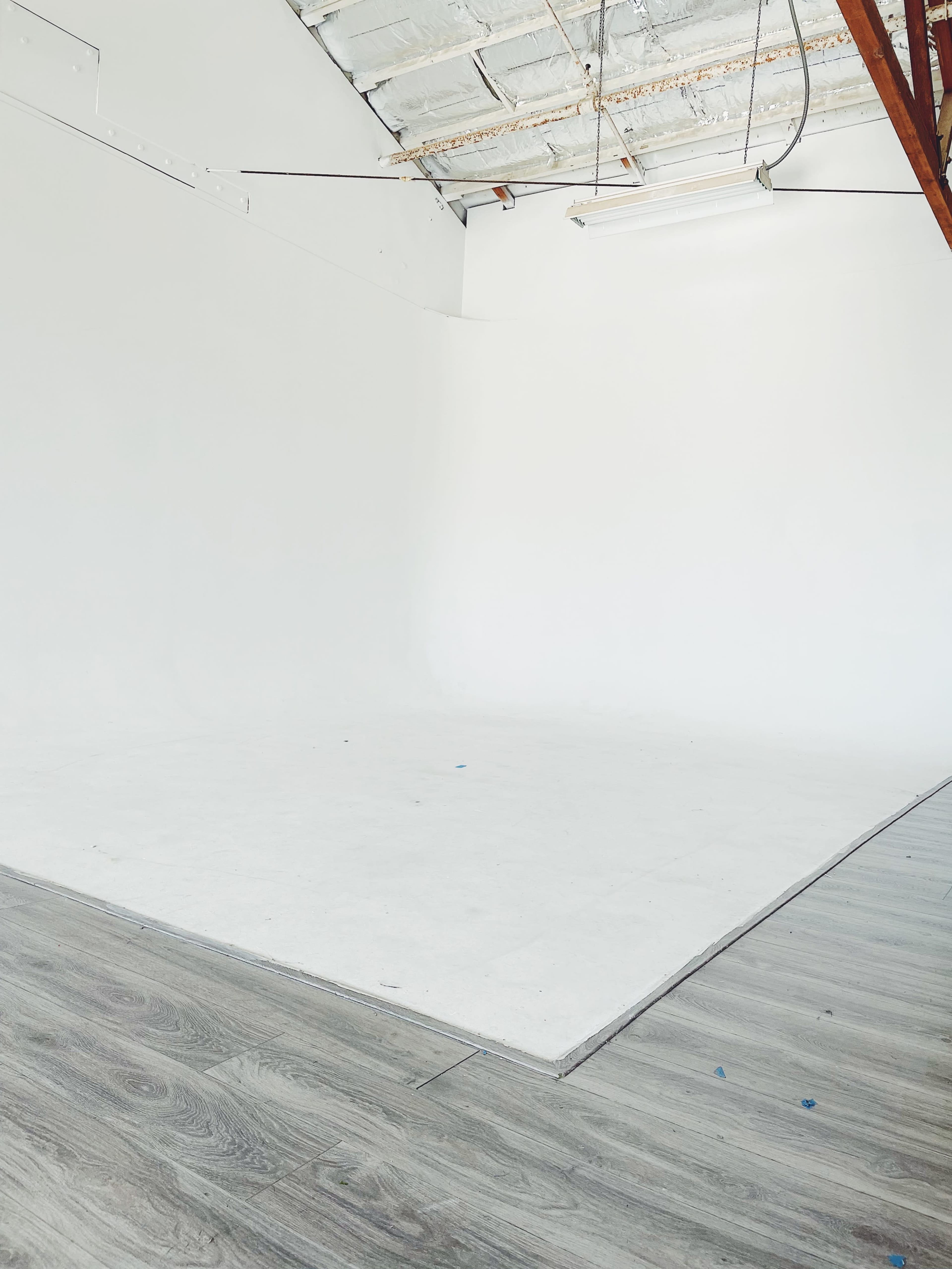 A spacious, empty studio with white walls and a light wood floor.